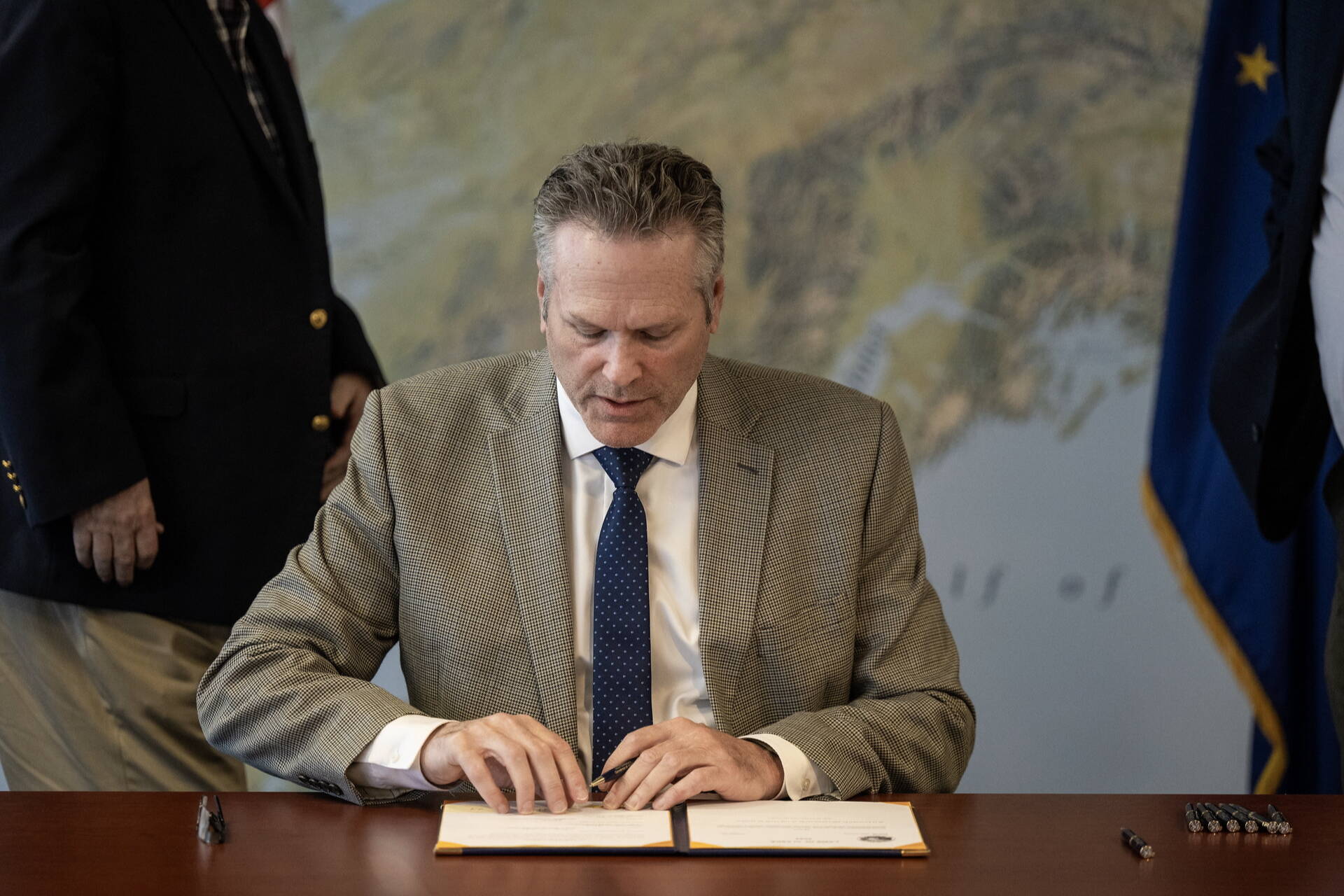 Gov. Mike Dunleavy signs bills for the state’s 2025 fiscal year budget during a private ceremony in Anchorage on Thursday. (Official photo from The Office of the Governor)