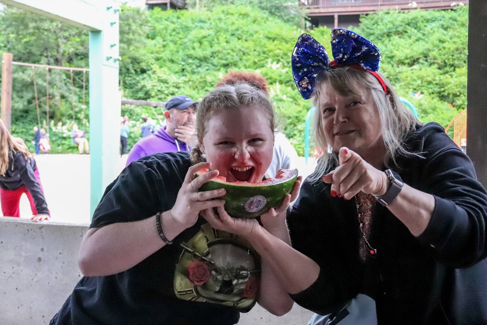 Brooklyn Kanouse (left) holds up her finished watermelon with pride at the watermelon-eating contest that happens during the Douglas Fourth of July Committee’s annual community picnic. (Jasz Garrett / Juneau Empire)