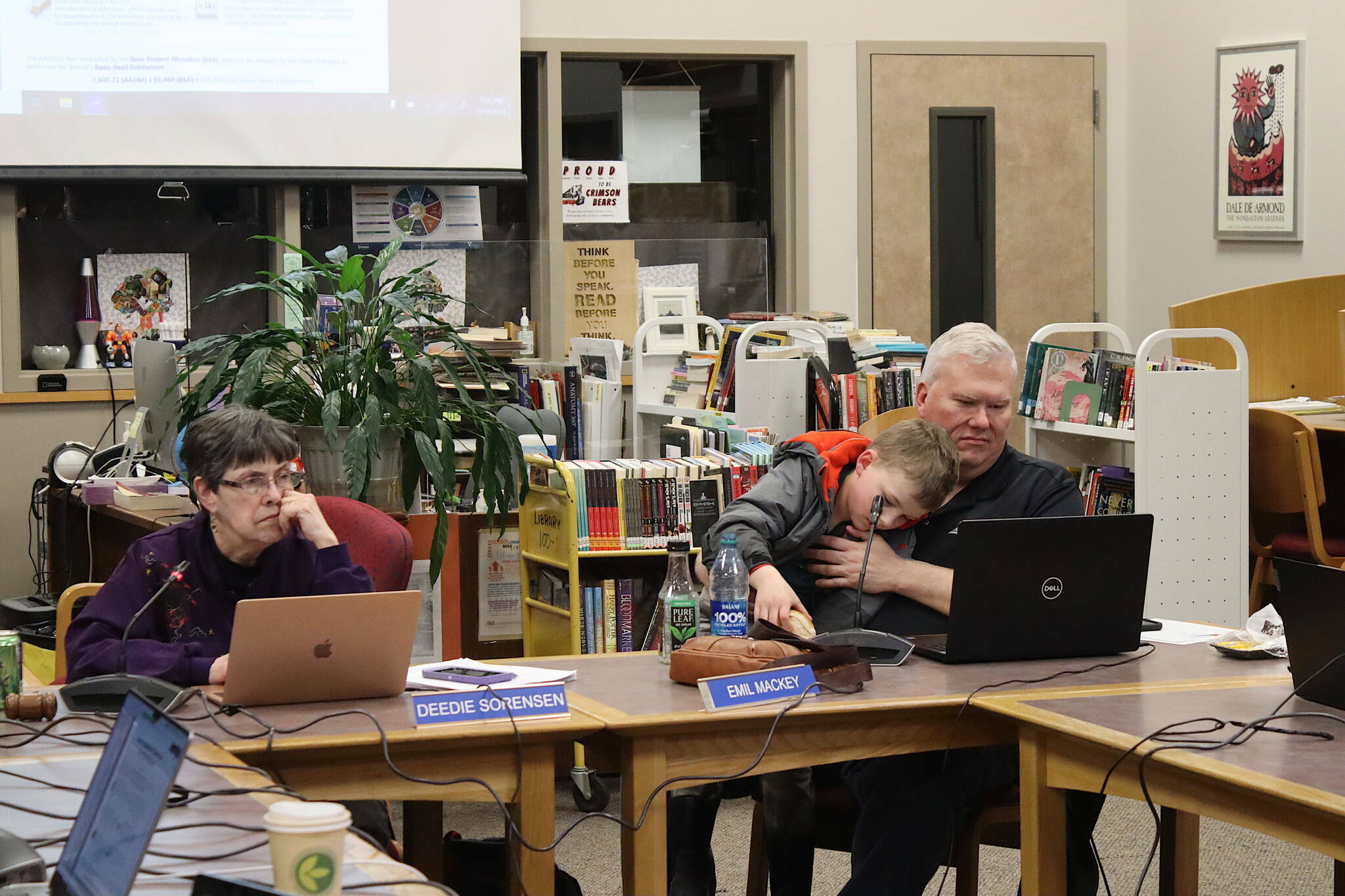 Juneau Board of Education President Deedie Sorensen (left) and Vice President Emil Mackey, holding his son Emil Mackey IV, listen to discussion about next year’s budget for the school district during a meeting March 14 at Juneau-Douglas High School: Yadaa.at Kalé. Recall votes for both board members were certified this week for the Oct. 1 municipal election ballot. (Mark Sabbatini / Juneau Empire file photo)