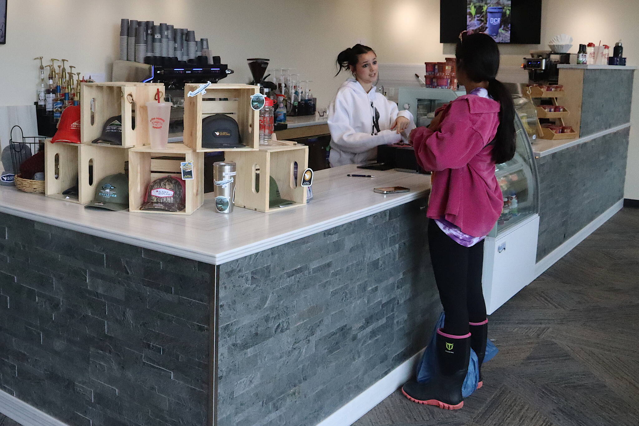 Disney Williams (right) orders coffee from Lorelai Bingham from the Flying Squirrel coffee stand at Juneau International Airport on Thursday. (Mark Sabbatini / Juneau Empire)