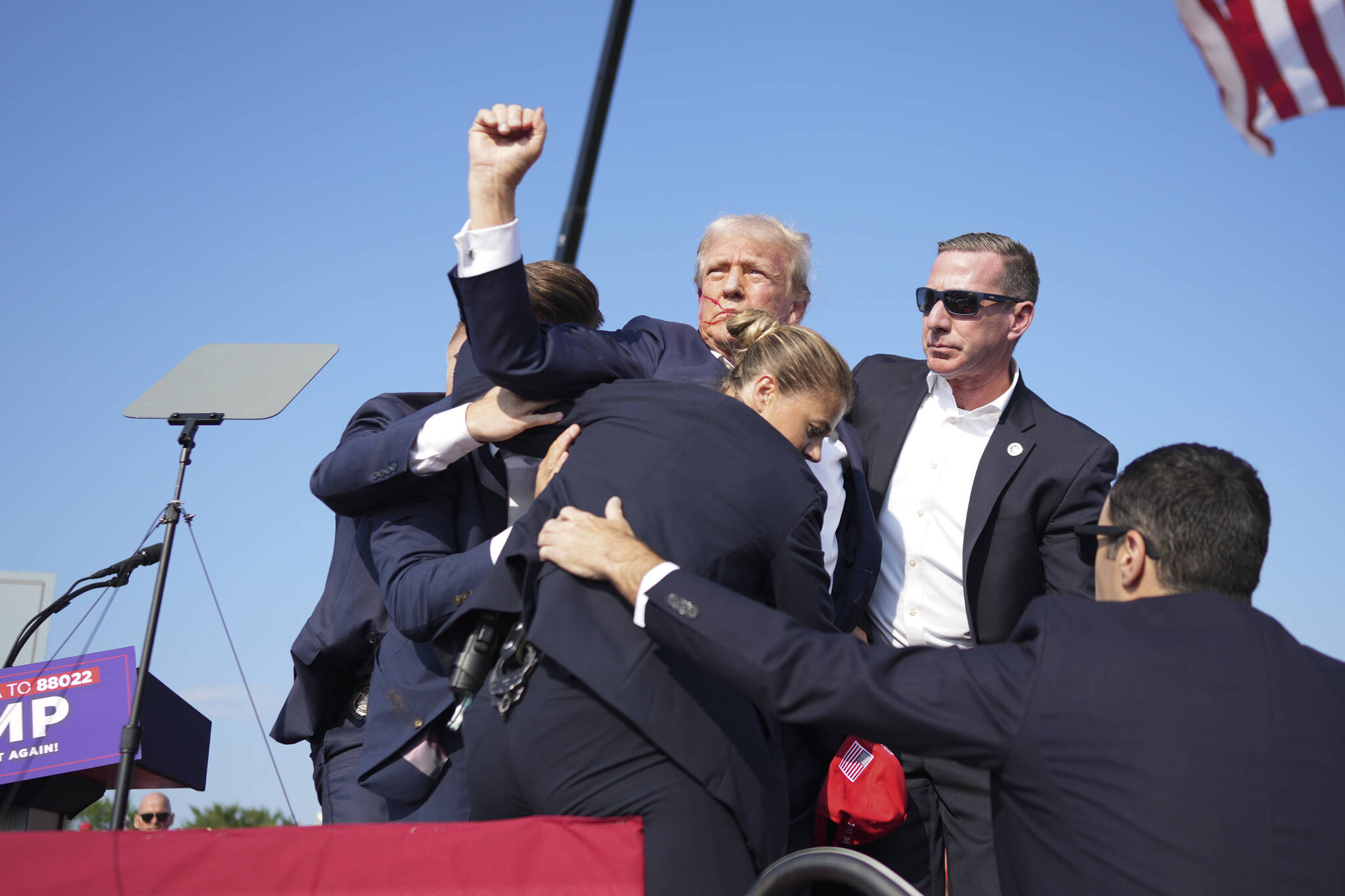 Former President Donald Trump is surrounded by Secret Service agents at a campaign rally in Butler, Pa, on Saturday. Trump was rushed off stage at rally after sounds like shots; the former president was escorted into his motorcade at his rally in Butler, Pa., a rural town about an hour north of Pittsburgh. (Doug Mills/The New York Times)