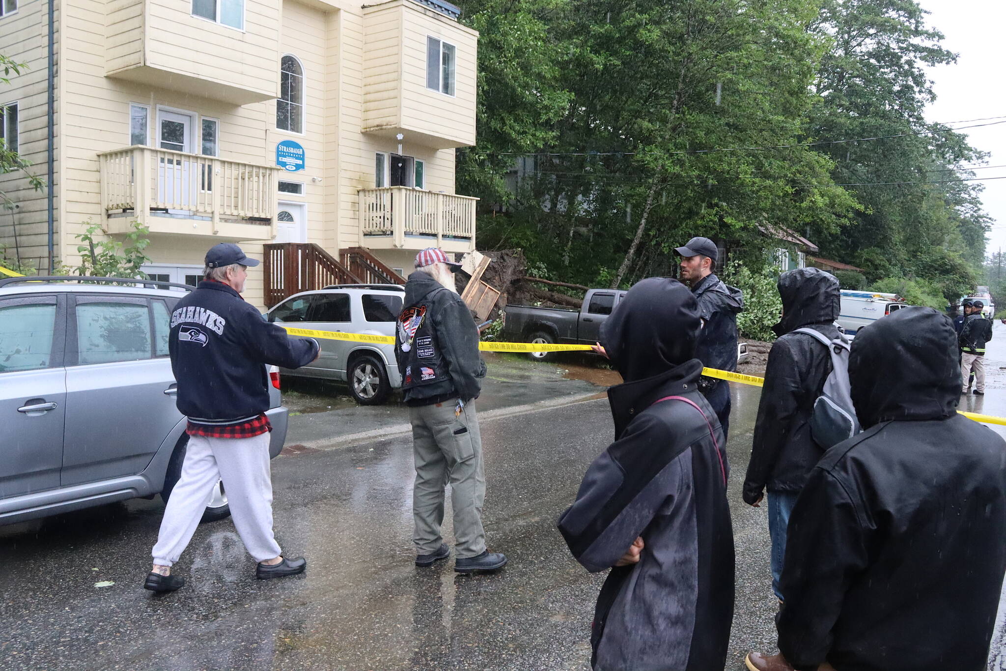 Residents of Strasbaugh Apartments on Gastineau Avenue and others in the neighborhood wait outside a sealed-off area Sunday morning after a landslide triggered by heavy rain hit the building. (Mark Sabbatini / Juneau Empire)