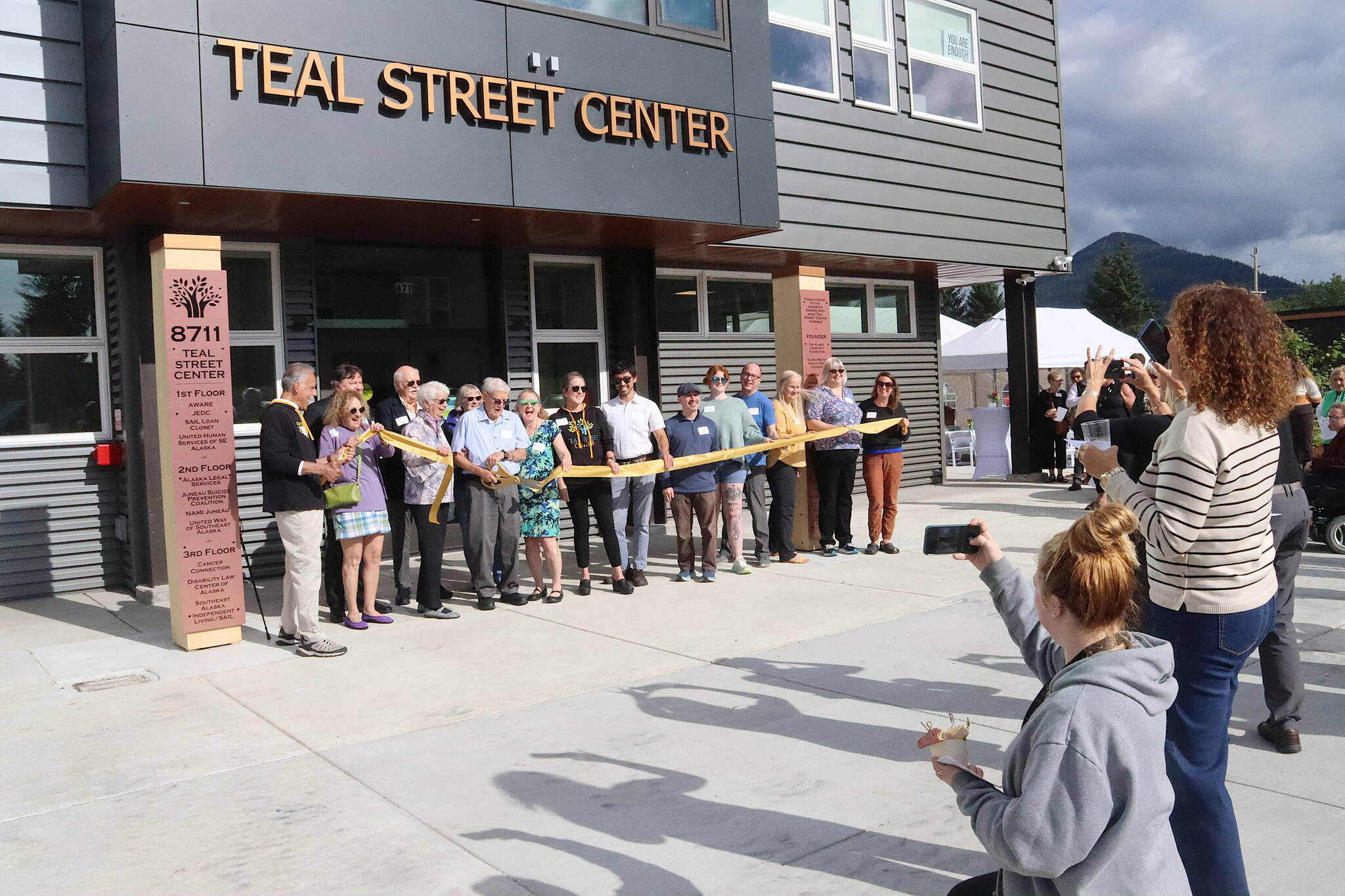 People take photos of local dignitaries during the ribbon-cutting ceremony at the Teal Street Center on Thursday afternoon. (Mark Sabbatini / Juneau Empire)
