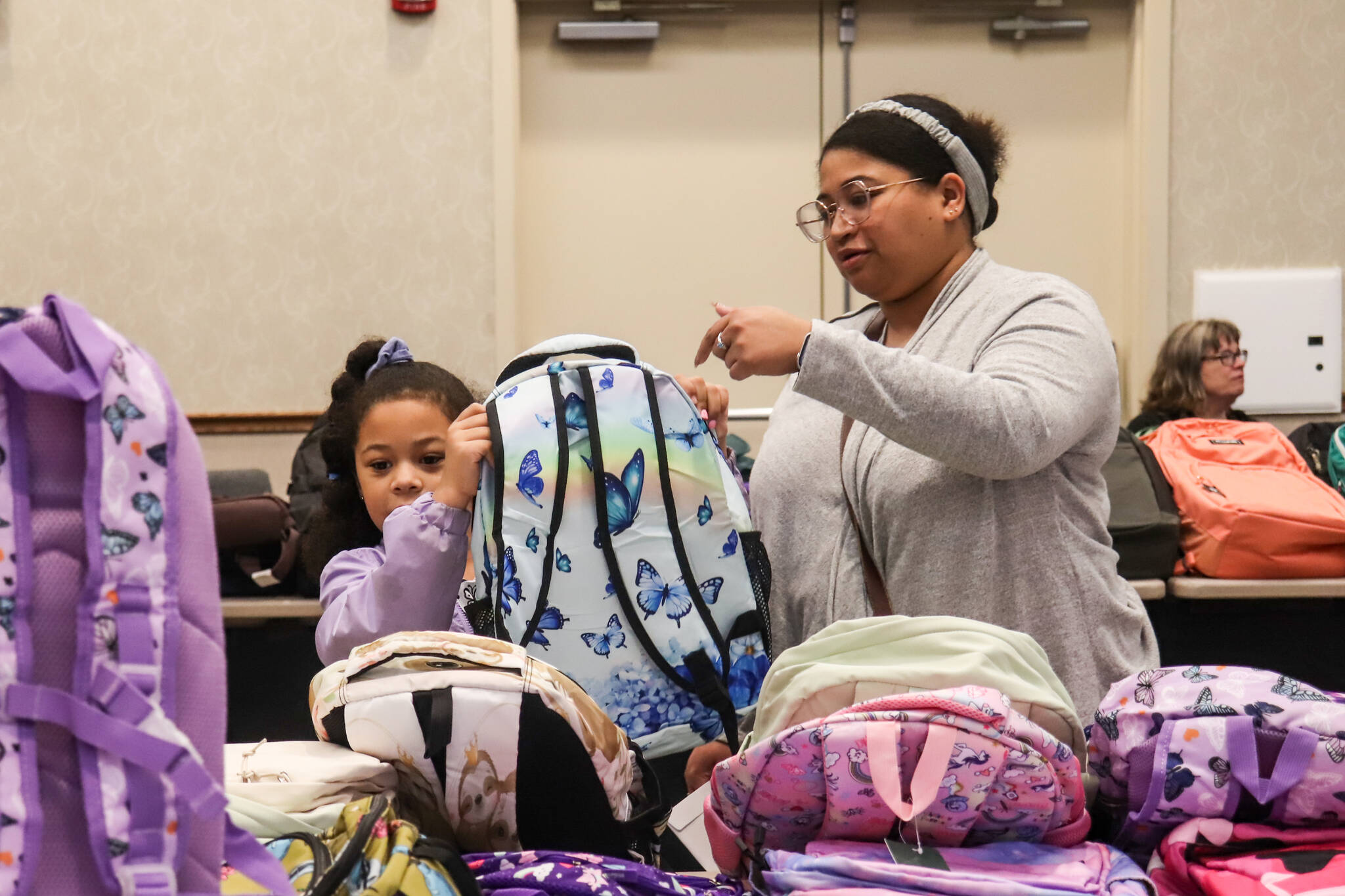 Charina and Taviana Cooper pick out a backpack on Saturday at Elizabeth Peratrovich Hall. (Jasz Garrett / Juneau Empire)