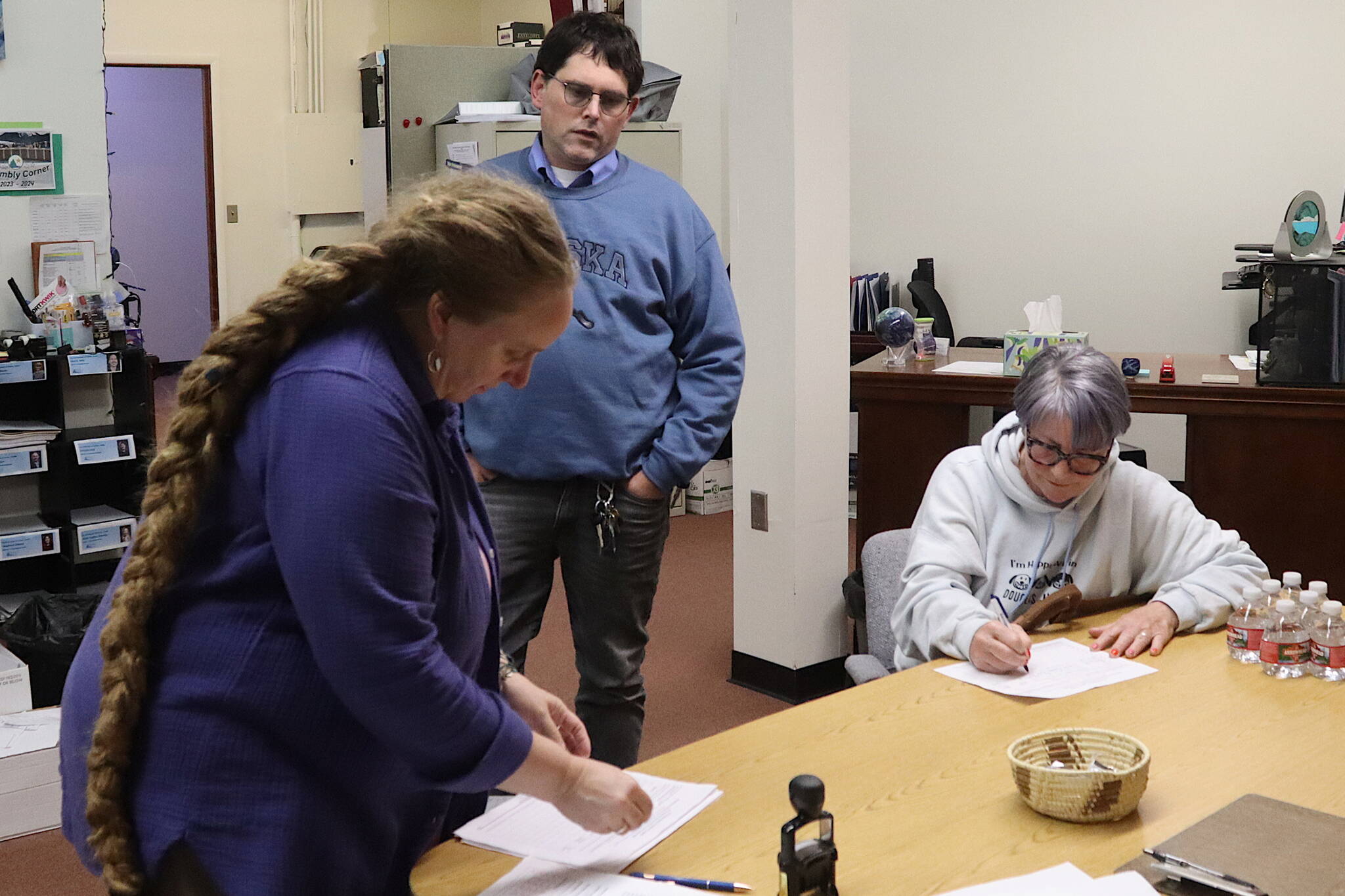 Michele Stuart Morgan (right), a Juneau Board of Education candidate, signs a qualifying petition for Jeff Redmond (center), who is also seeking one of three school board seats in the Oct. 1 municipal election, just before Monday’s filing deadline at City Hall. At left, Deputy Municipal Clerk Diane Cathcart processes last-minute paperwork filed by candidates. (Mark Sabbatini / Juneau Empire)