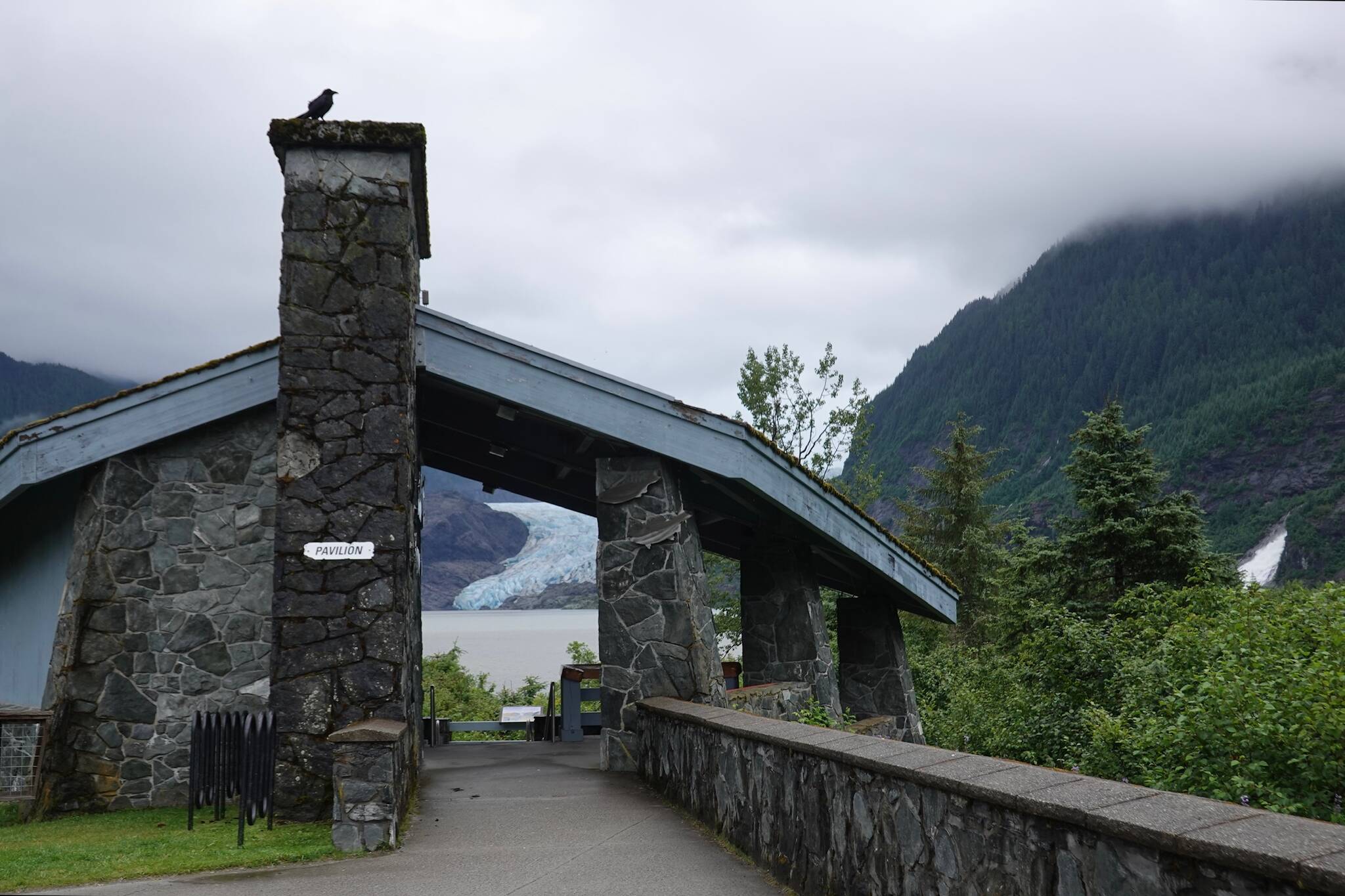 Cloudy sky silhouettes a solitary raven near Mendenhall Glacier Visitor Center early Tuesday morning as the bird perched atop the U.S. Forest Service pavilion framing the glacier’s blue ice across Mendenhall Lake. (Laurie Craig / Juneau Empire file photo)