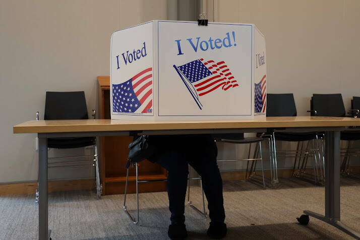 A voter sits behind a privacy screen while filling out a ballot during the City and Borough of Juneau 2022 municipal election. (Clarise Larson / Juneau Empire file photo)