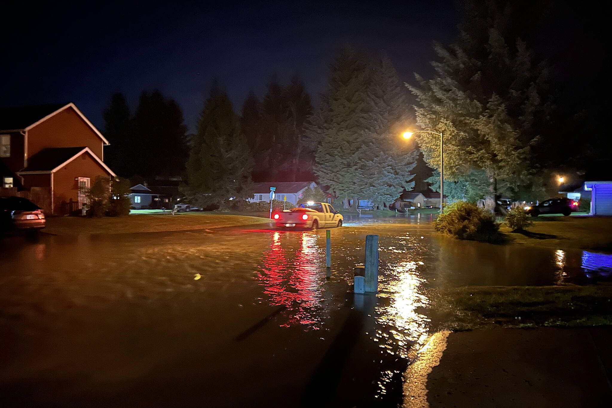 Vehicles try to navigate through rapidly rising flood waters in a neighborhood along the Mendenhall River at about 1 a.m. on Tuesday. (Jasz Garrett / Juneau Empire)