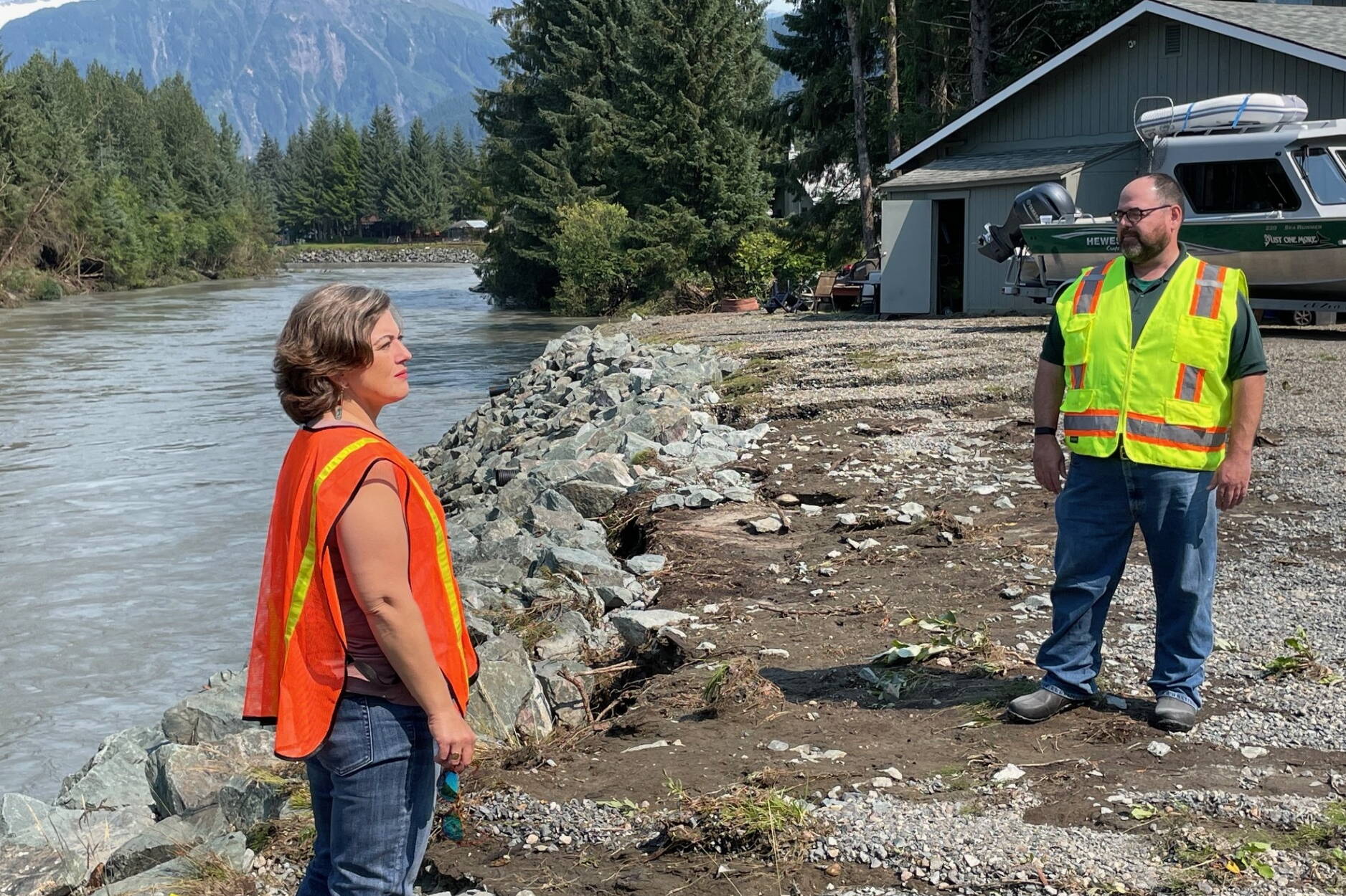 Jill Lawhorne, community development director for the City and Borough of Juneau, and building inspector Jeff Hedges examine a section of armored riverbank that had minimal damage despite a fast-flowing drainage of water from the Meander Way neighborhood during record flooding Monday and Tuesday. A nearby homeowner reported the only damage to her home was a gash in the garage where a large spruce tree rammed into the exterior and poked a sizable hole that allowed water to get into the garage. (Laurie Craig / Juneau Empire)