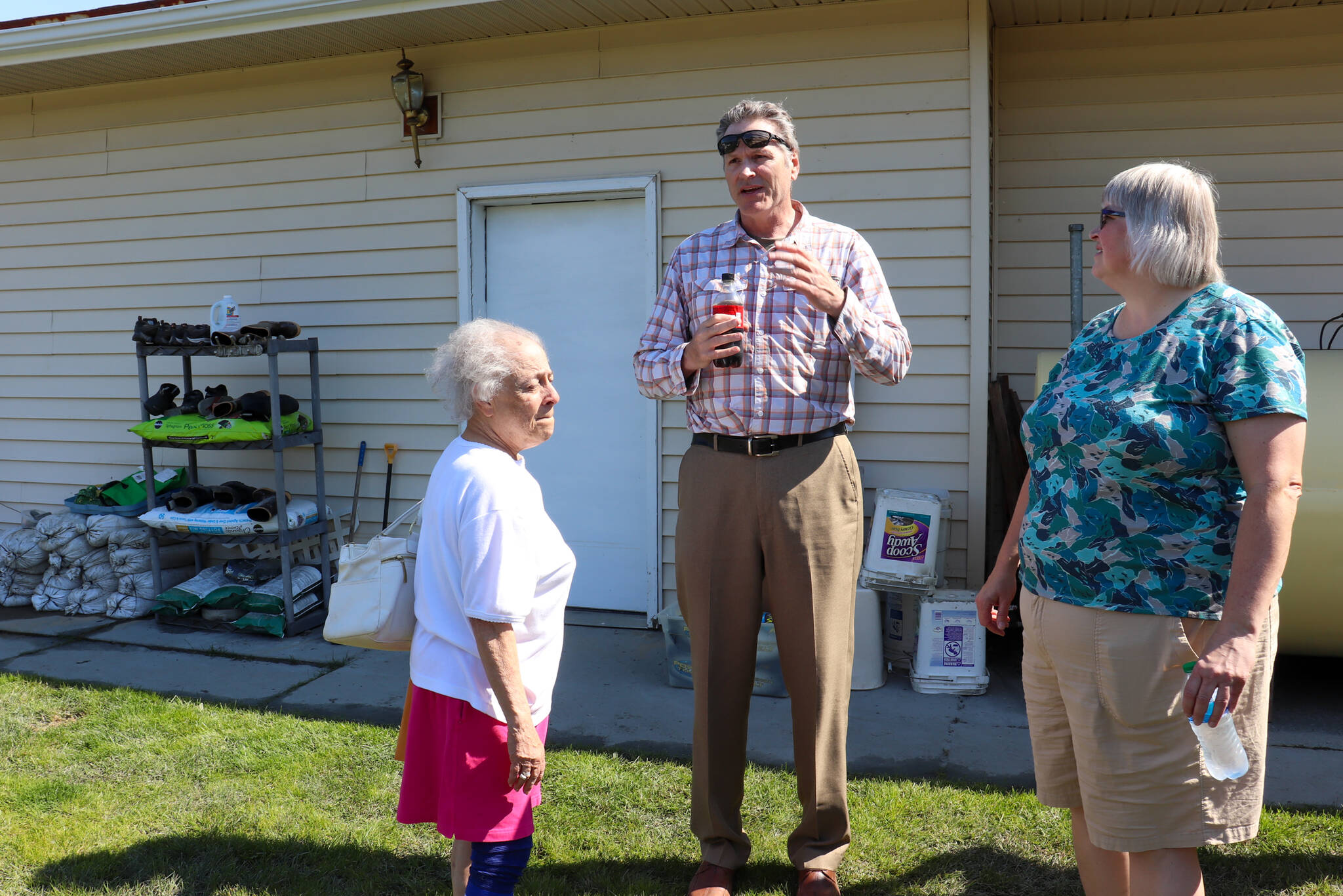 Gov. Mike Dunleavy and Mayor Beth Weldon chat with Janet Coffin outside her home on Killewich Drive on Wednesday afternoon. (Jasz Garrett / Juneau Empire)