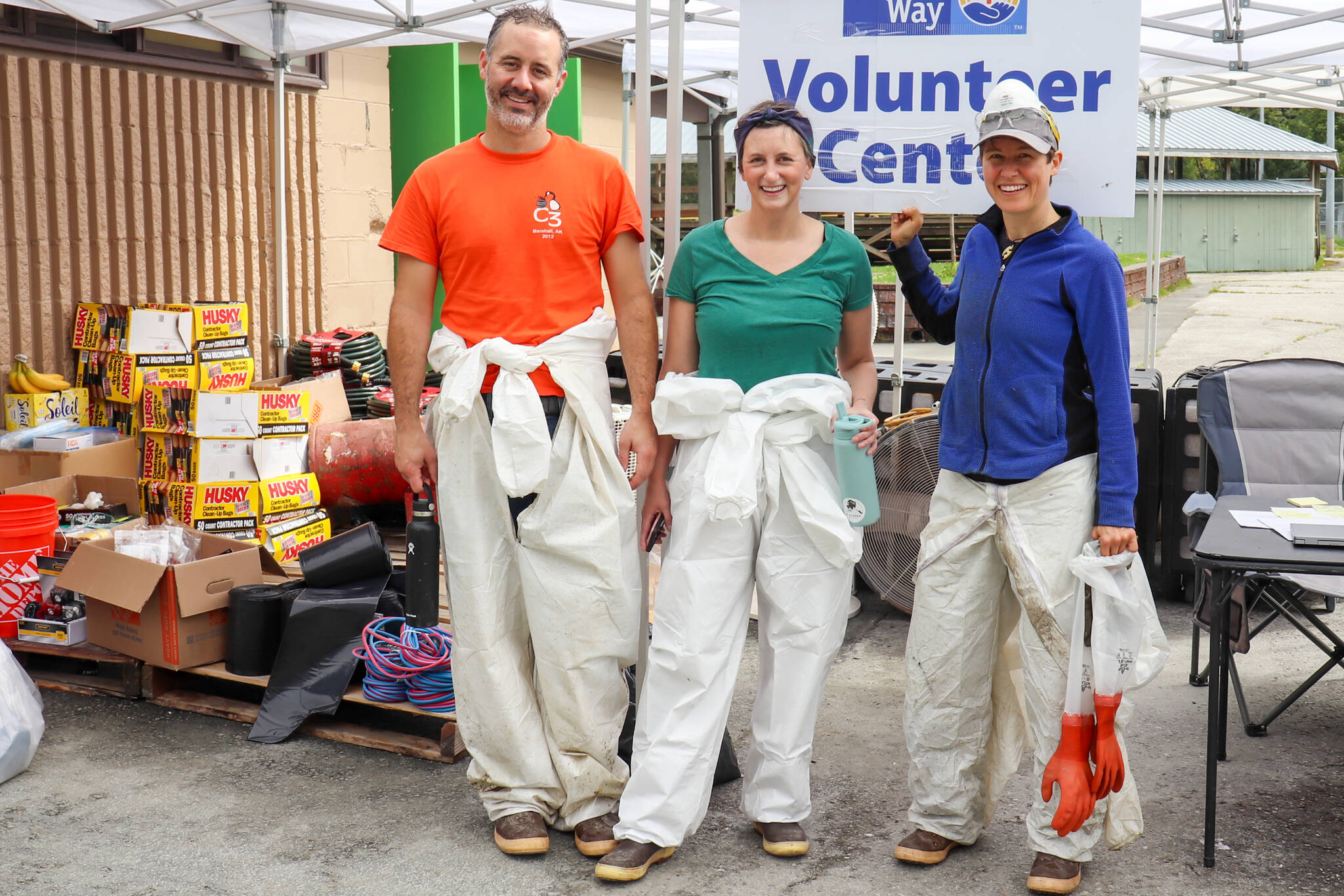 From left to right: Jeff Smith, Tanna Peters and Gwenna Corvez return for food after finishing pulling insulation out of two crawlspaces in a row on Saturday morning. (Jasz Garrett / Juneau Empire)