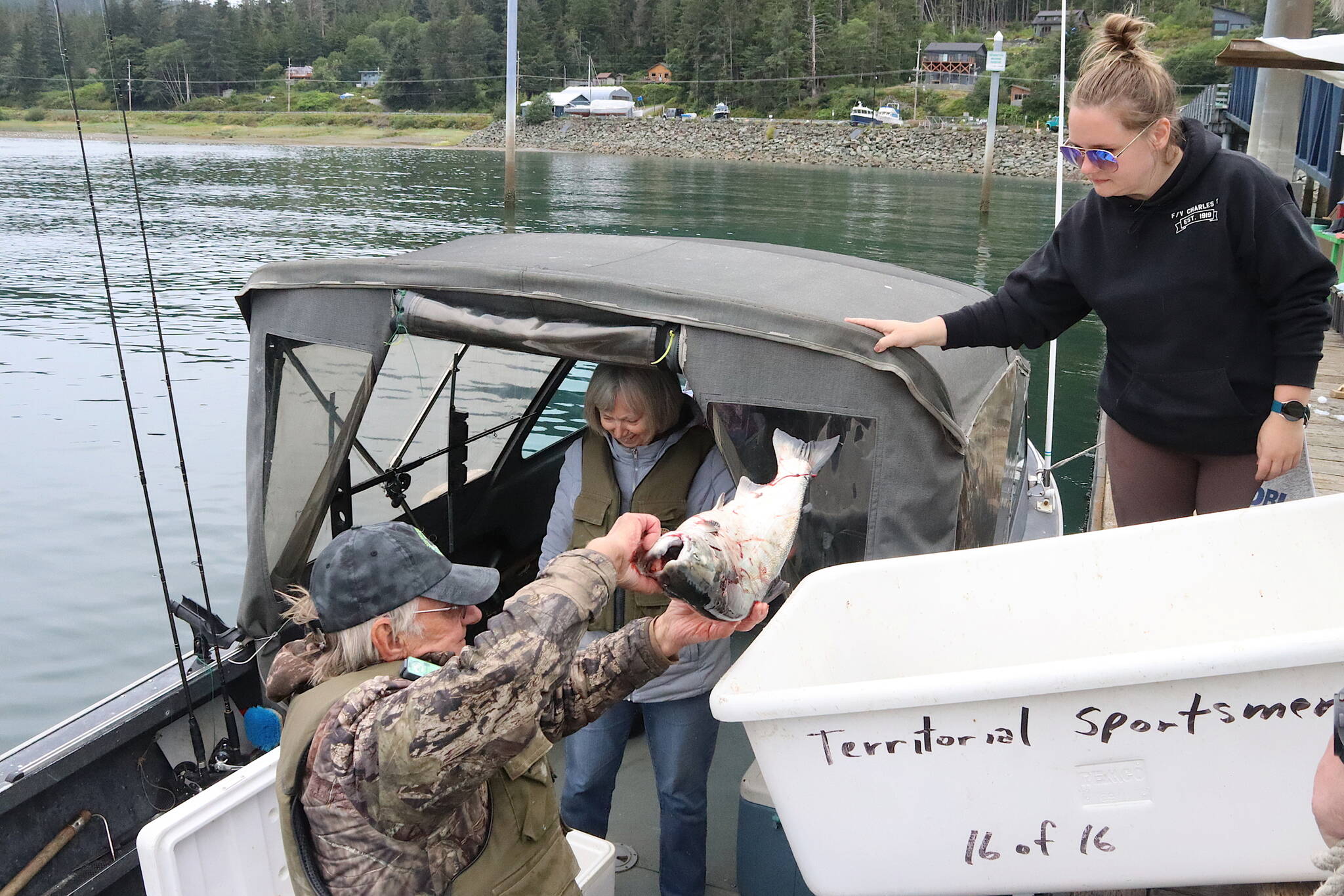 Mike Bethers and his wife, Astrid, turn over two fish to Alysha Reeves, dock chair at the Auke Nu weighing station during the final day of the 78th annual Golden North Salmon Derby on Sunday. (Mark Sabbatini / Juneau Empire)