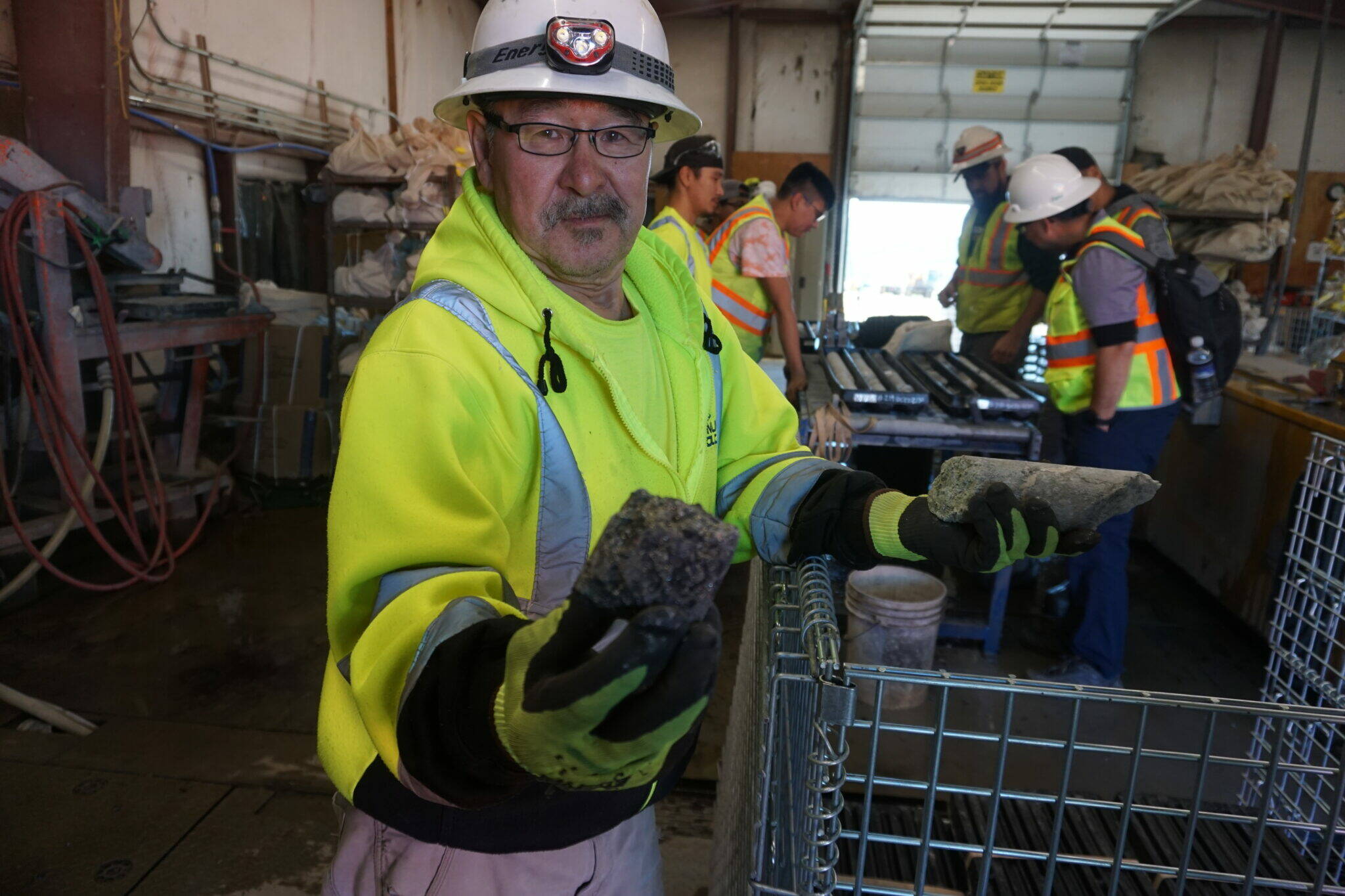 Yago Jacob of Napaskiak, one of the Calista Corp. shareholders employed at the Donlin Gold project, holds up a sliced piece of a geological core on Aug. 11, 2022. Calista is the Native corporation that owns the mineral rights at the mine project. Donlin is one of eight large mine projects listed in a new report as being near development or in advanced exploration. Seven large Alaska mines currently are producing. (Yereth Rosen/Alaska Beacon)