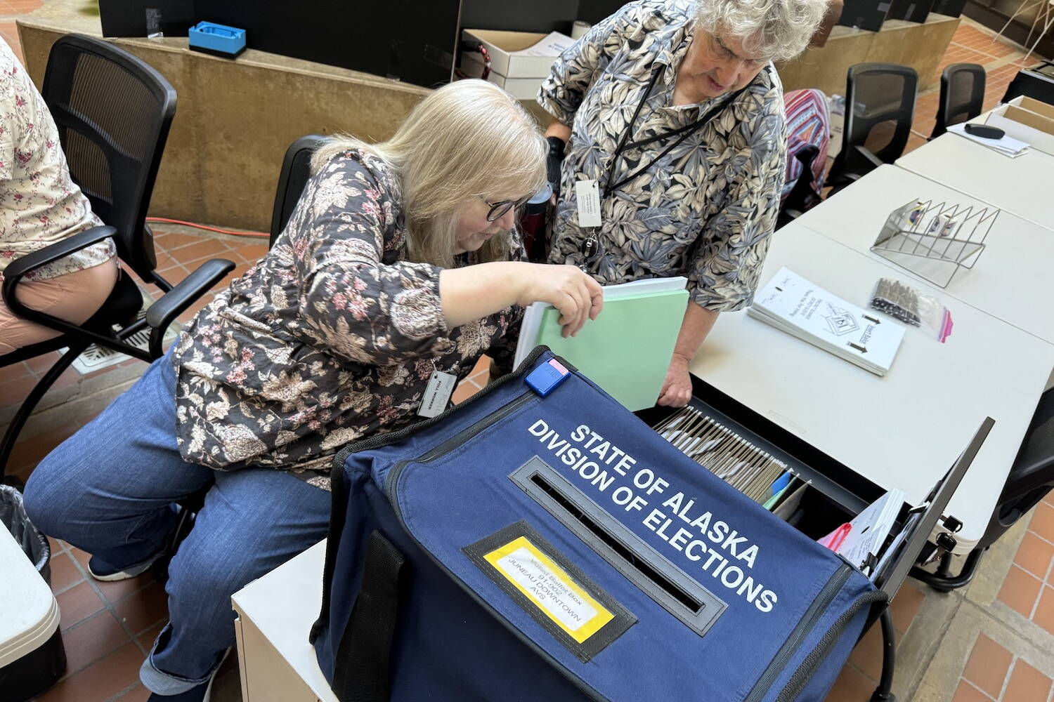 Poll workers set up an early voting statiion in the atrium of the State Office Building in Juneau on Monday, Aug. 5, 2024, the first day of early voting for the 2024 Alaska primary election. (James Brooks/Alaska Beacon)