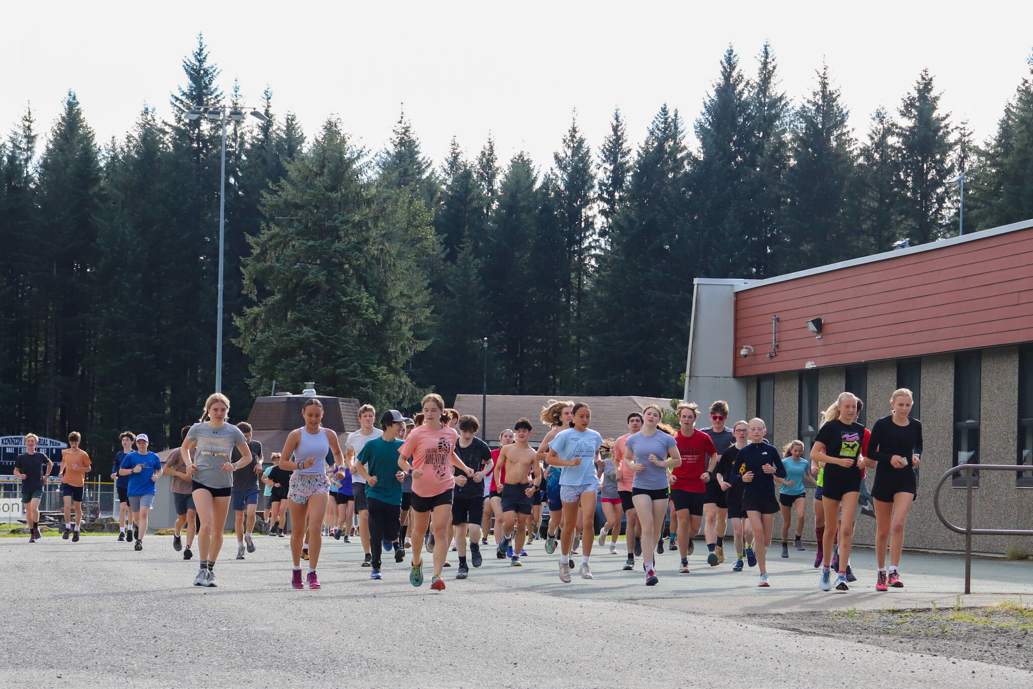 The Juneau-Douglas High School: Yadaa.at Kalé cross-country team runs toward the Under Thunder Trail from Floyd Dryden Middle School on Monday evening for a team practice. (Jasz Garrett / Juneau Empire)