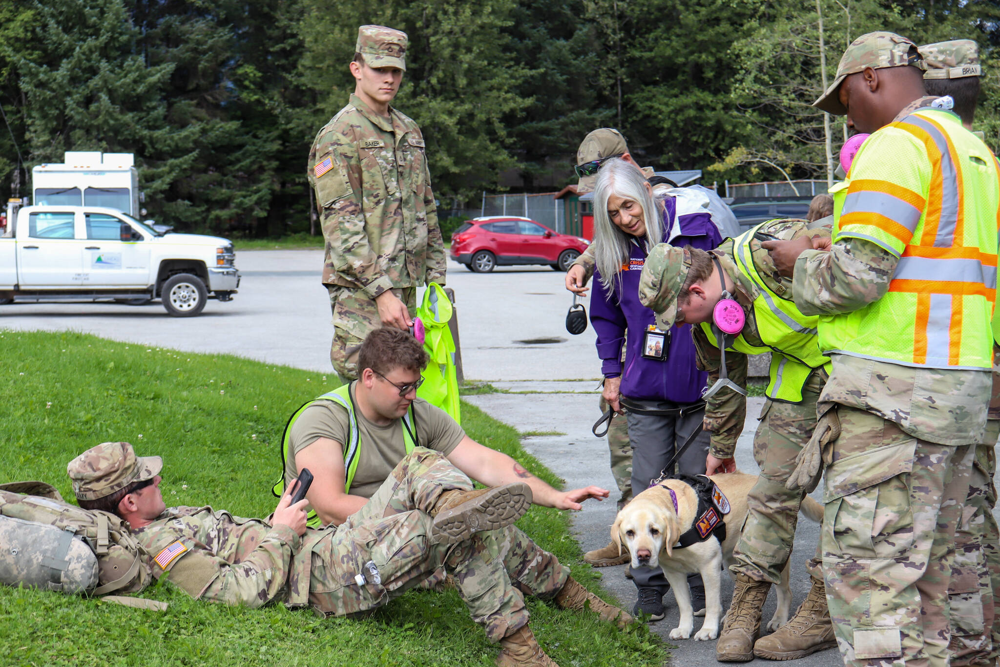 Alaska National Guard members spend time with Tia, a certified National Crisis Response canine visiting Juneau from Anchorage to offer support at the Melvin Park volunteer disaster center on Wednesday. (Jasz Garrett / Juneau Empire)