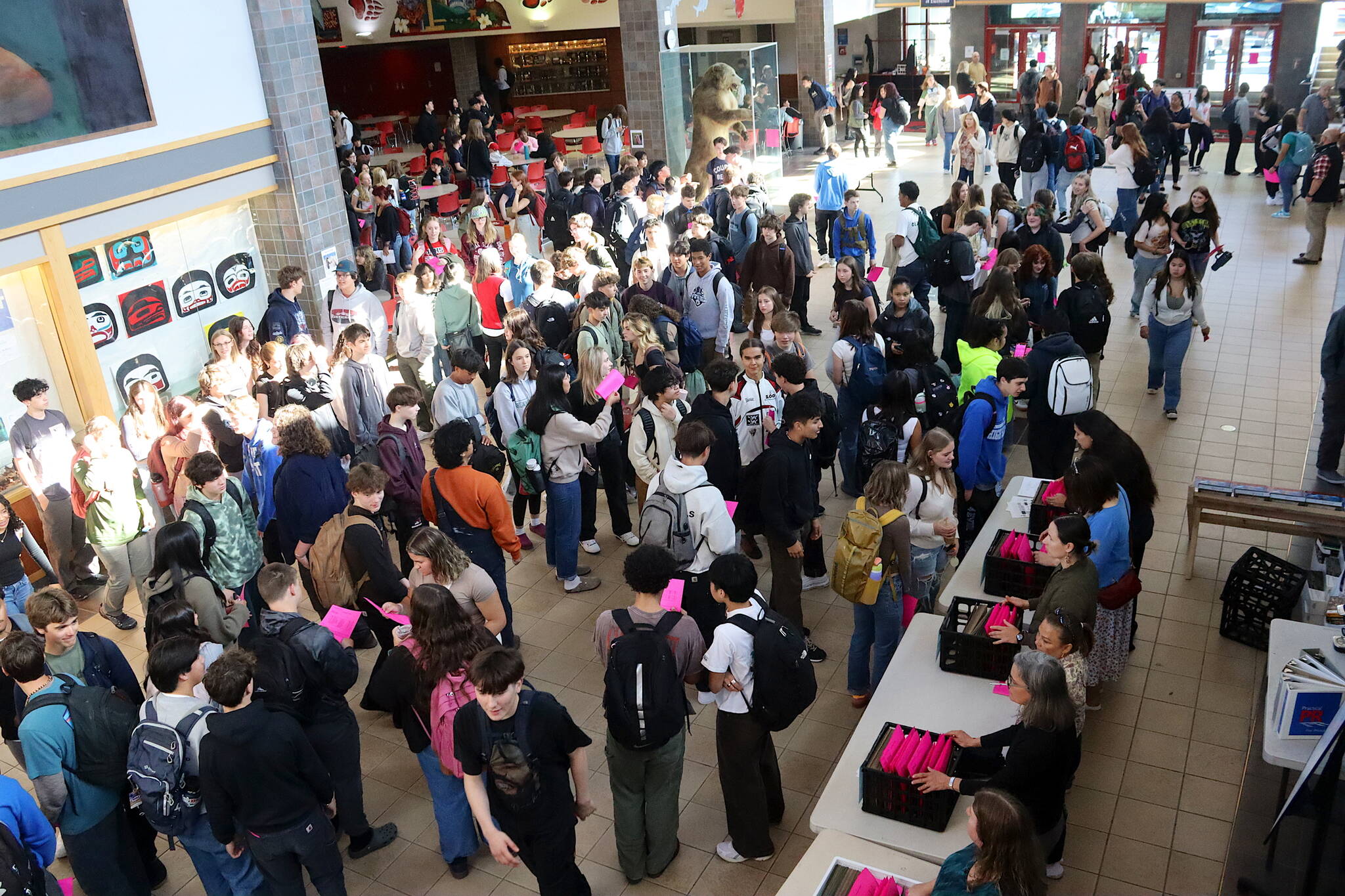 Students crowd into the commons area of Juneau-Douglas High School: Yadaa.at Kalé to pick up their schedules, and meet familiar and new peers, before classes start on the first day of school Thursday morning. (Mark Sabbatini / Juneau Empire)