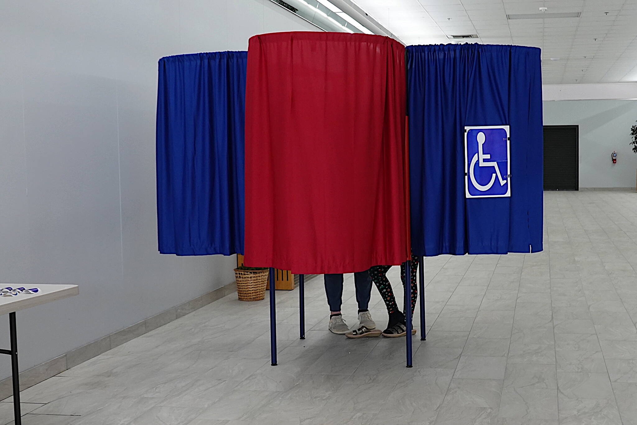 A father and daughter share a private voting booth to fill out his official white ballot and her special green ballot on Saturday at the Mendenhall Mall Annex. Only the official ballot is processed. (Laurie Craig / Juneau Empire)