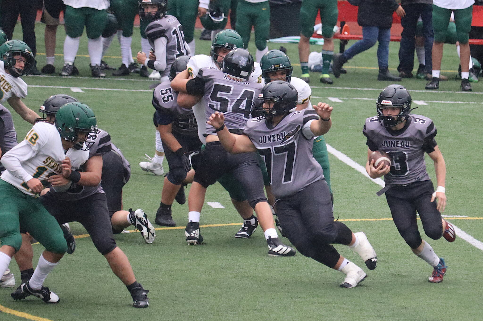 Juneau-Douglas High School: Yadaa.at Kalé linemen Ricky Tupou, (77), Jonah Mahle (54), Walter Haube-Law (55) and Benny Zukas (58) block for Ethan Van Kirk (3) during Saturday’s game against Service High School at Adair-Kennedy Memorial Park. (Mark Sabbatini / Juneau Empire)