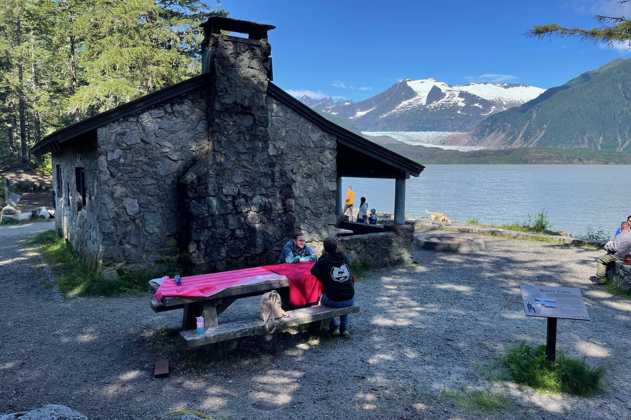 A gathering of friends rent Skater’s Cabin on Mendenhall Lake from the U.S. Forest Service on a sunny day in July of 2024. The cabin and the West Glacier Trail beyond it were Civilian Conservation Corps projects. (Laurie Craig / Juneau Empire)