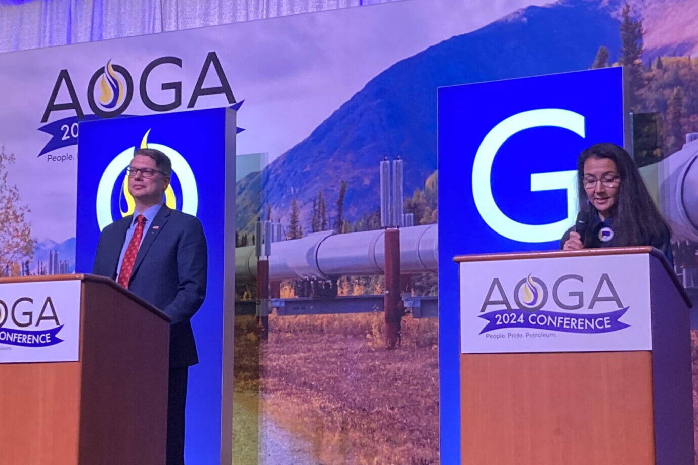 Republican challenger Nick Begich III and Democratic U.S. Rep. Mary Peltola are on the stage at the beginning of the Alaska Oil and Gas Association’s candidate forum on Aug. 28, 2024. (Andrew Kitchenman/Alaska Beacon)