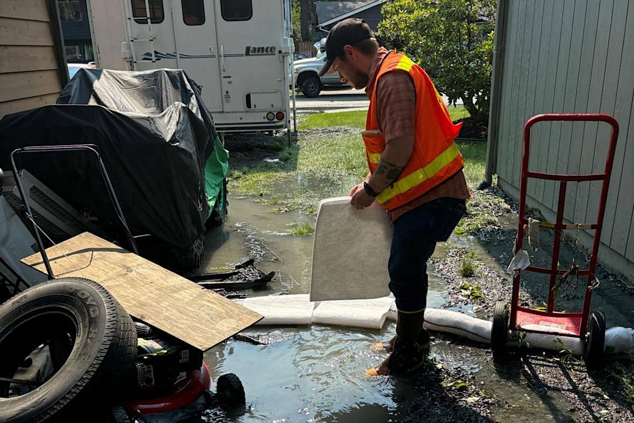 A worker examines a flooded yard where fuel and other hazardous material may have spilled. (Alaska Department of Environmental Conservation photo)