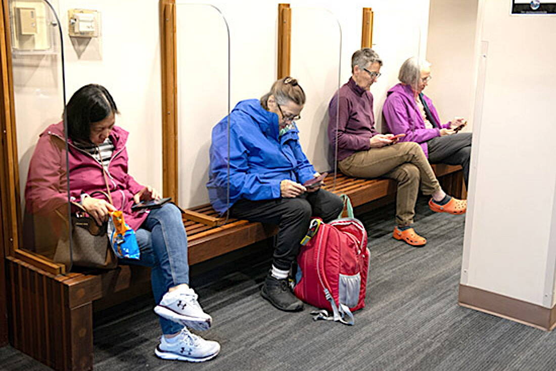 Sitkans sit in the lobby of city hall on Saturday as they use the city’s satellite connection to the internet with their cell phones. (Sitka Sentinel photo)