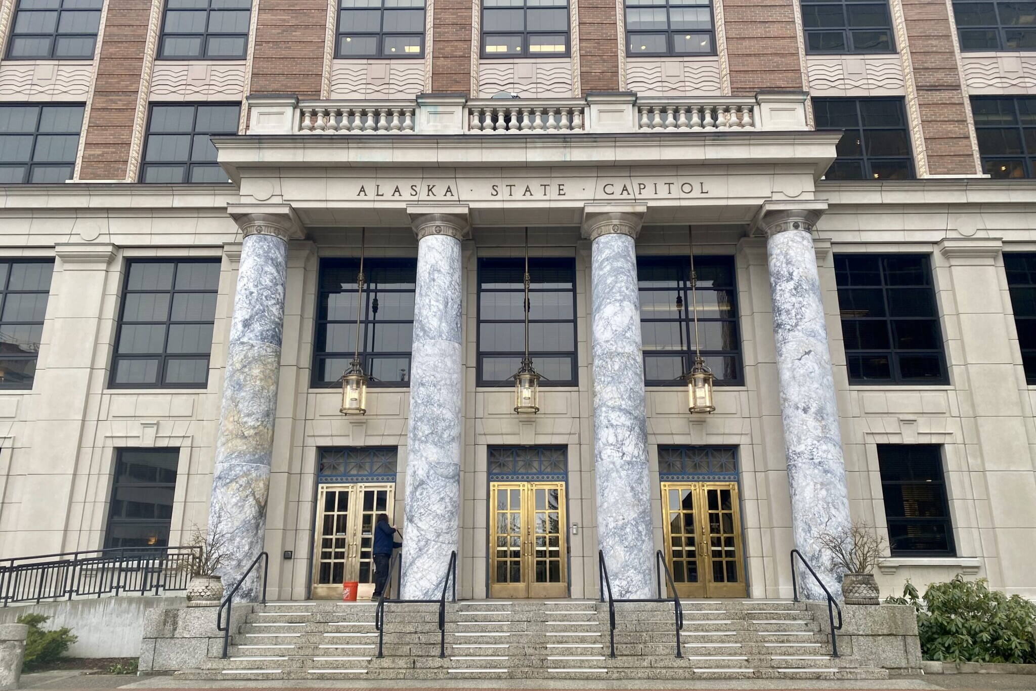 A maintenance worker cleans the front of the Alaska State Capitol in Juneau on April 2, 2024. (Claire Stremple/Alaska Beacon)