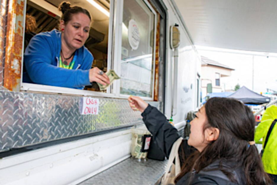 Kari Cravens, of Ashmo’s food truck in Sitka, takes cash from Jacil Lee, a cruise ship passenger stopping in town last week. Many business owners in Sitka are unable to accept credit and debit cards amid an outage in most phone and internet communications. (Sitka Sentinel, republished with permission)