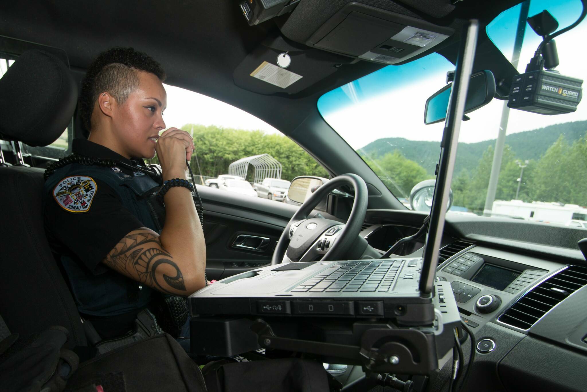 City and Borough of Juneau photo
A Juneau Police Department officer talks on a radio in a patrol car. Officials said JPD’s communications system, which had an end-of-life date in 2014, needs to be replaced to provide improvements such as full radio coverage within the city and borough limits.