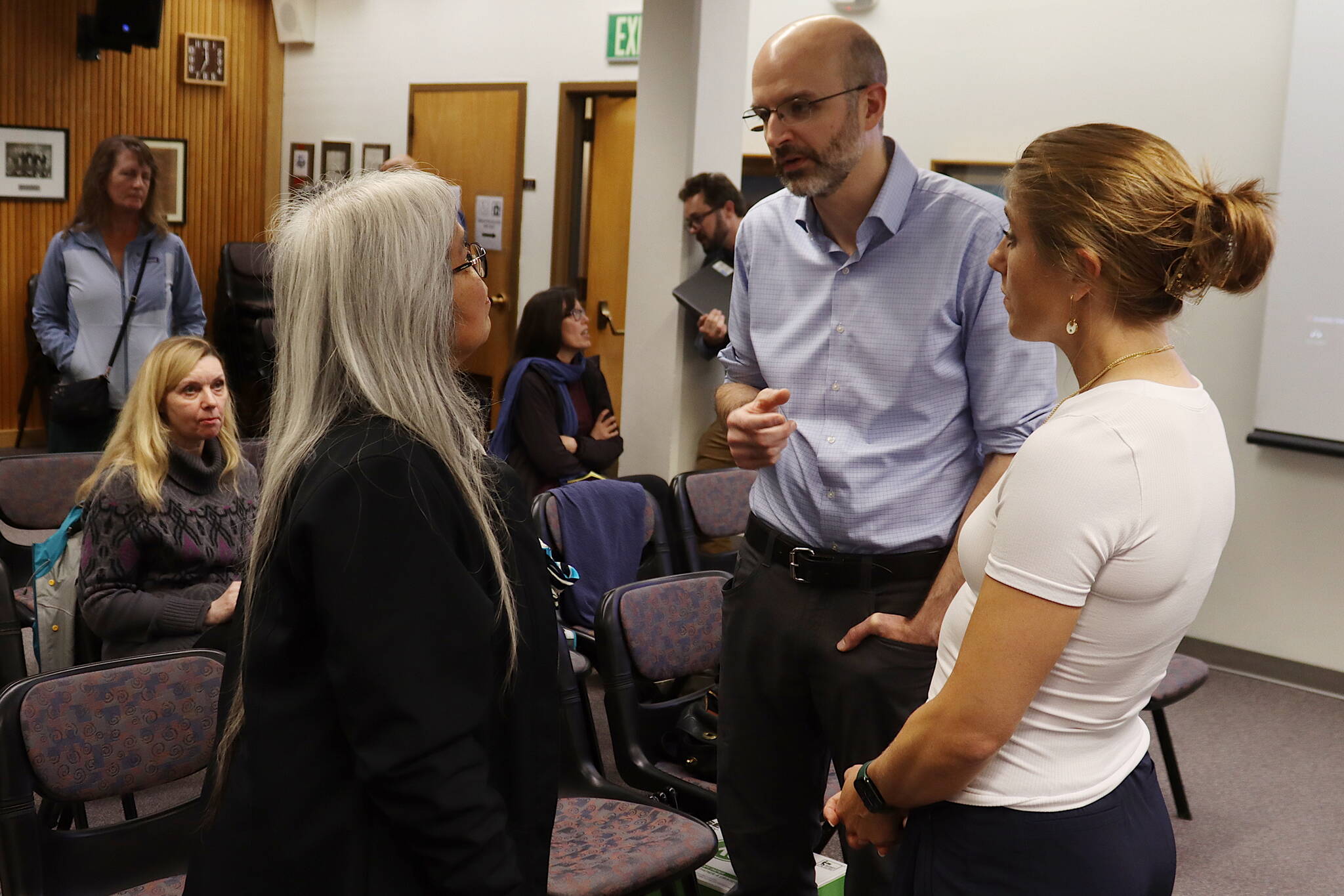 Juneau City Manager Katie Koester (right) and Deputy City Manager Robert Barr discuss the possibility of another flood this year from Suicide Basin with Mary Marks, a Juneau Assembly candidate, during a meeting of the Assembly’s Committee of the Whole on Monday night. (Mark Sabbatini / Juneau Empire)