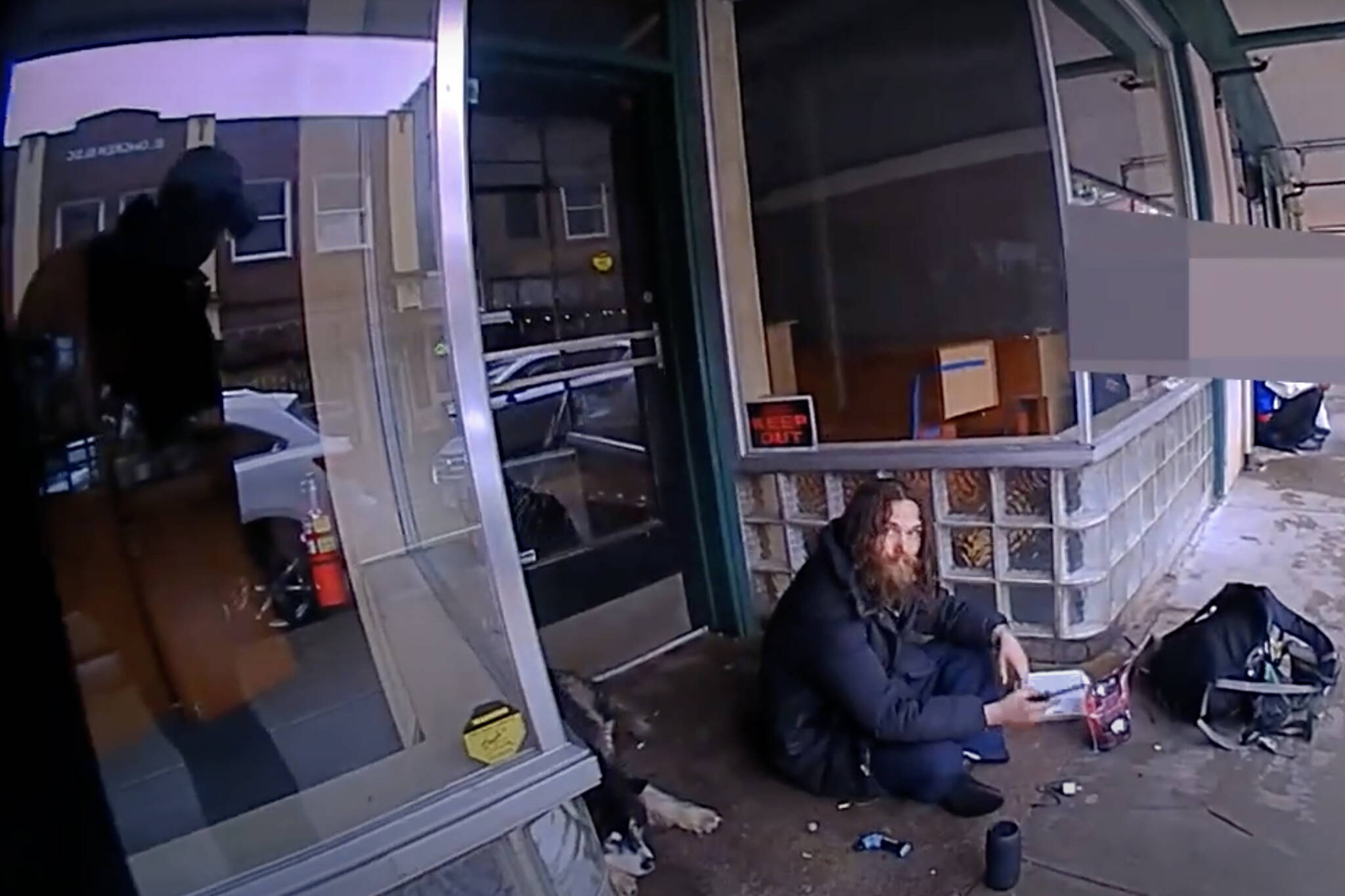 Steven Kissack, sitting in a covered entryway on Front Street, is approached by Juneau Police Department officer Lee Phelps at about 1:10 p.m. July 15. (Screenshot from Phelps’s bodycam video)