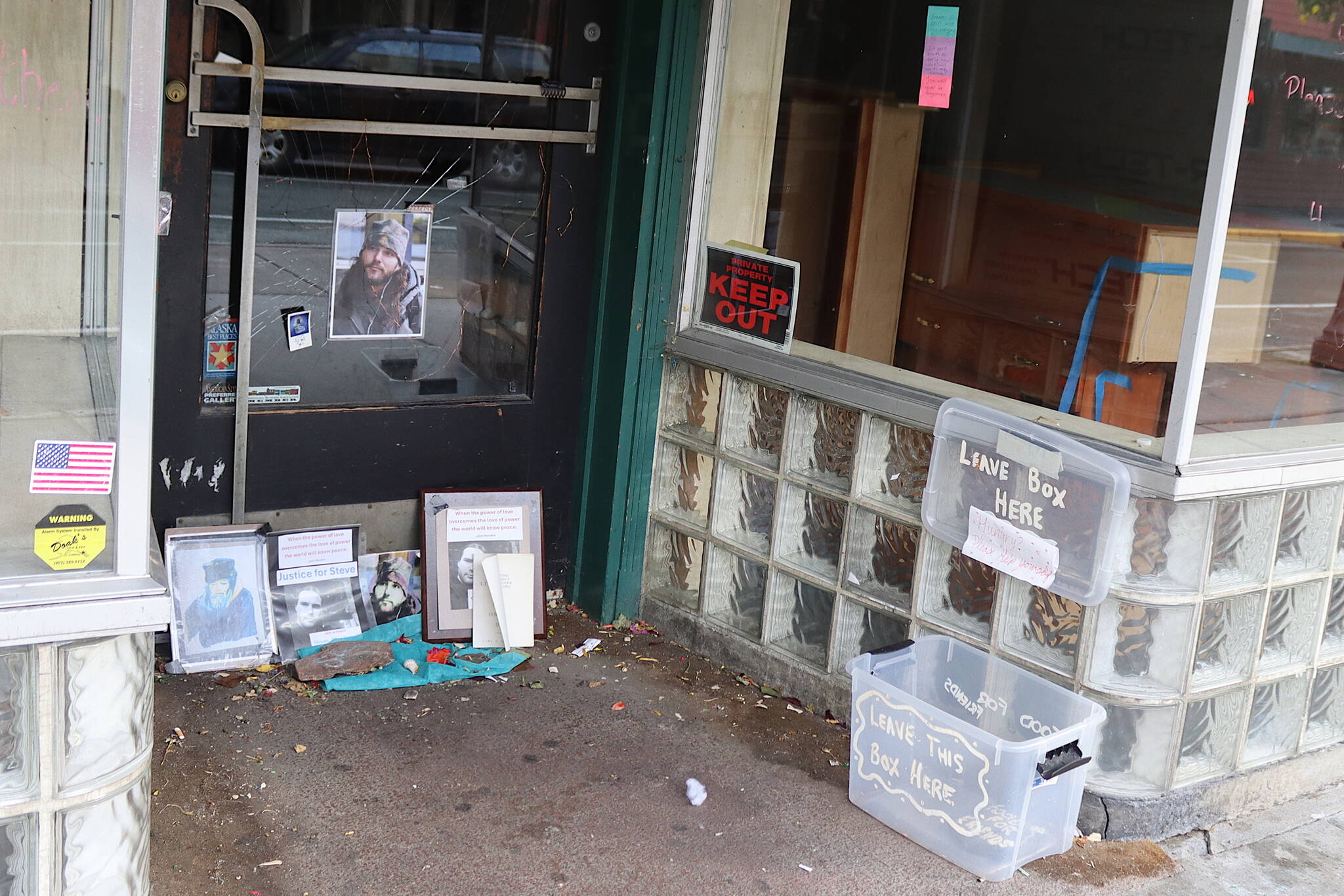 A memorial in the doorway on Front Street where Steven Kissack was sitting when he was approached by a police officer on July 15, resulting in a 16-minute encounter that ended with him being fatally shot, includes photos, written messages and a “food for friends” dropoff box on Saturday morning. (Mark Sabbatini / Juneau Empire)