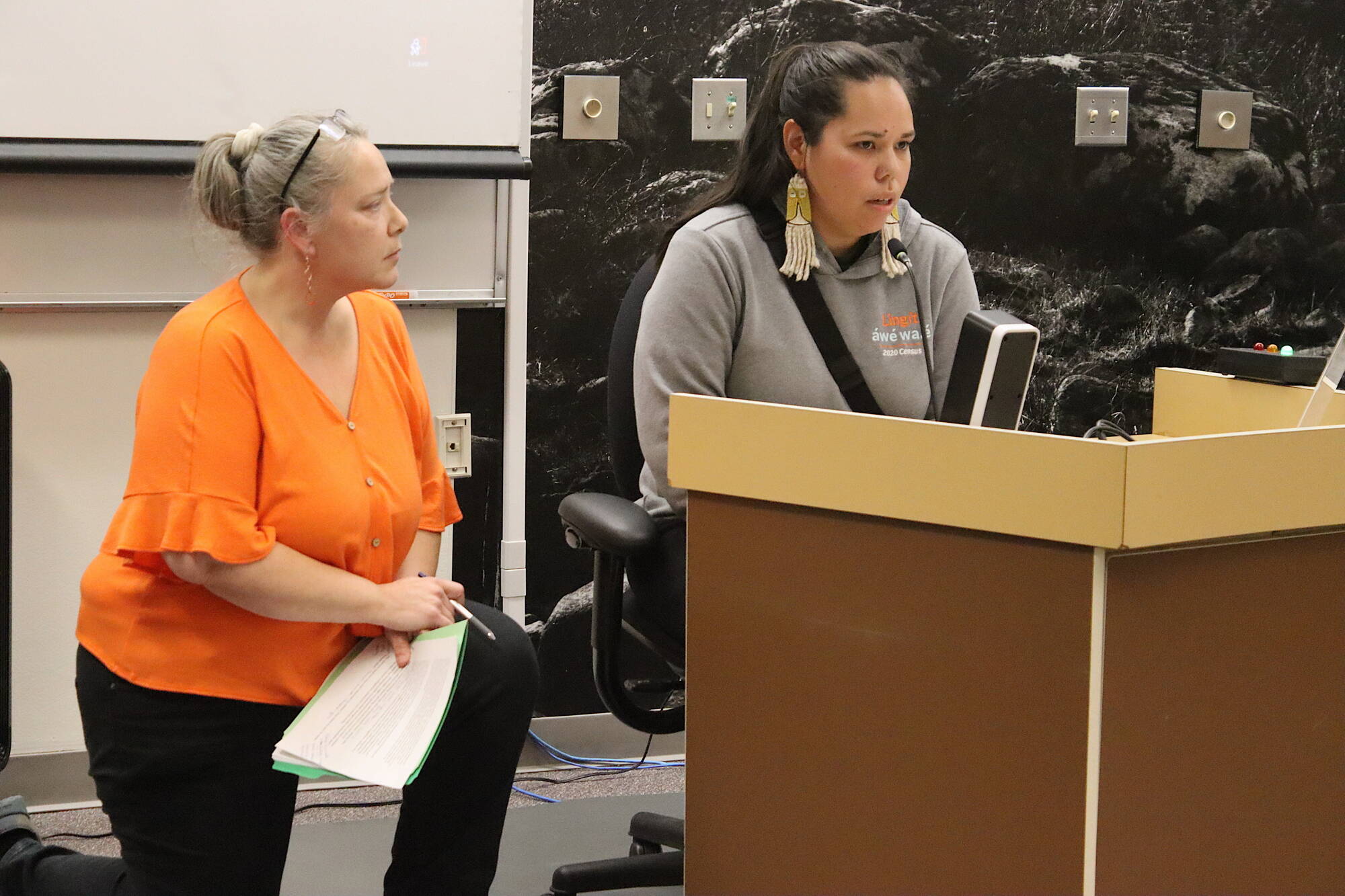 Samia Savell (right) offers public testimony about Suicide Basin flooding concerns while Sandra Edwardson, who testified immediately before Savell, offers support during a Juneau Assembly meeting on Monday night. (Mark Sabbatini / Juneau Empire)