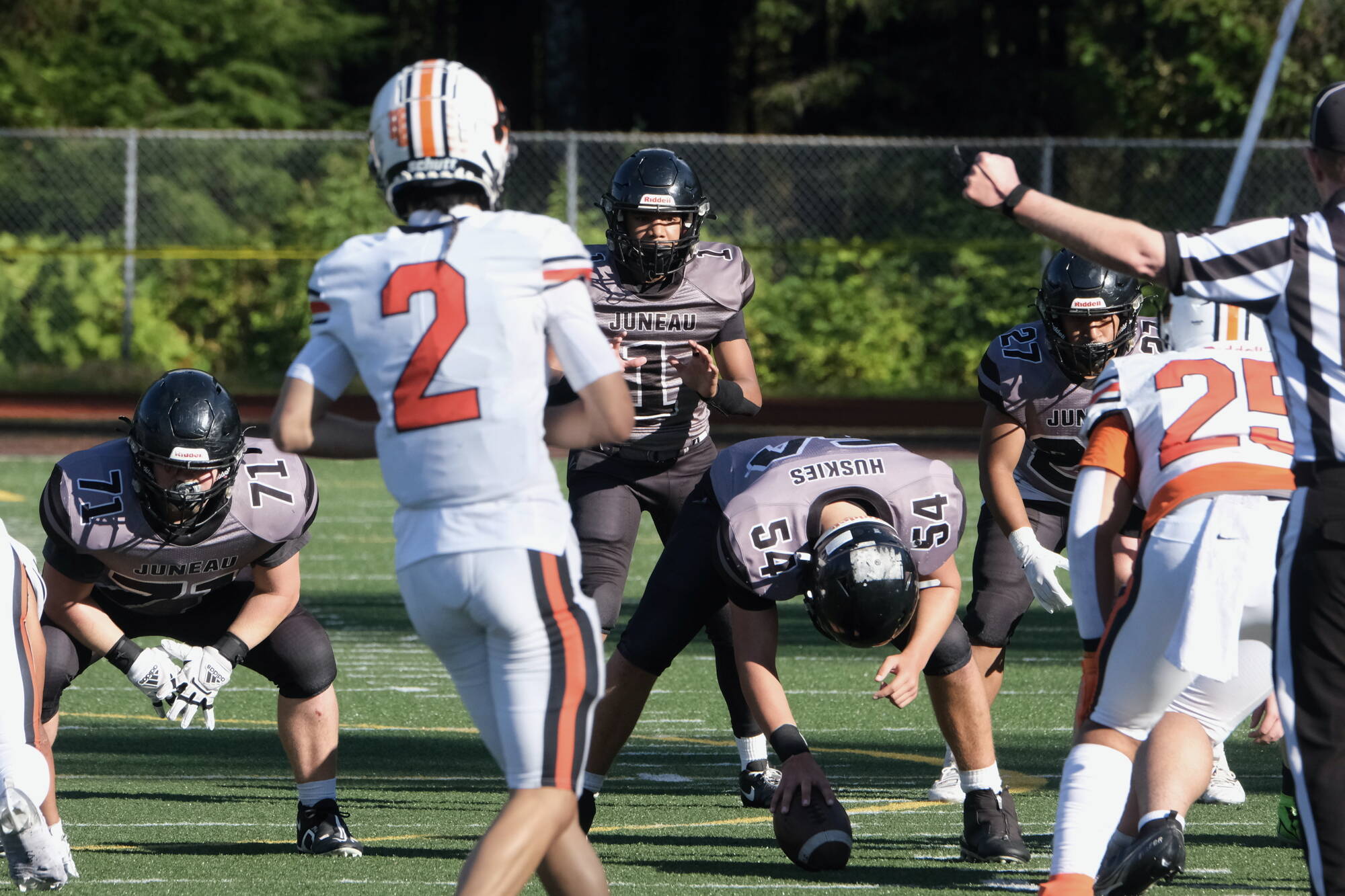 Juneau Huskies junior quarterback Noah Ault (1) awaits the snap from junior center Jonah Mahle (54) as junior offensive lineman Kyle Carter (71) and junior running back Samuel Sarof (27) await action during a game against West Anchorage at Adair-Kennedy Memorial Park earlier this season. (Klas Stolpe / For the Juneau Empire)