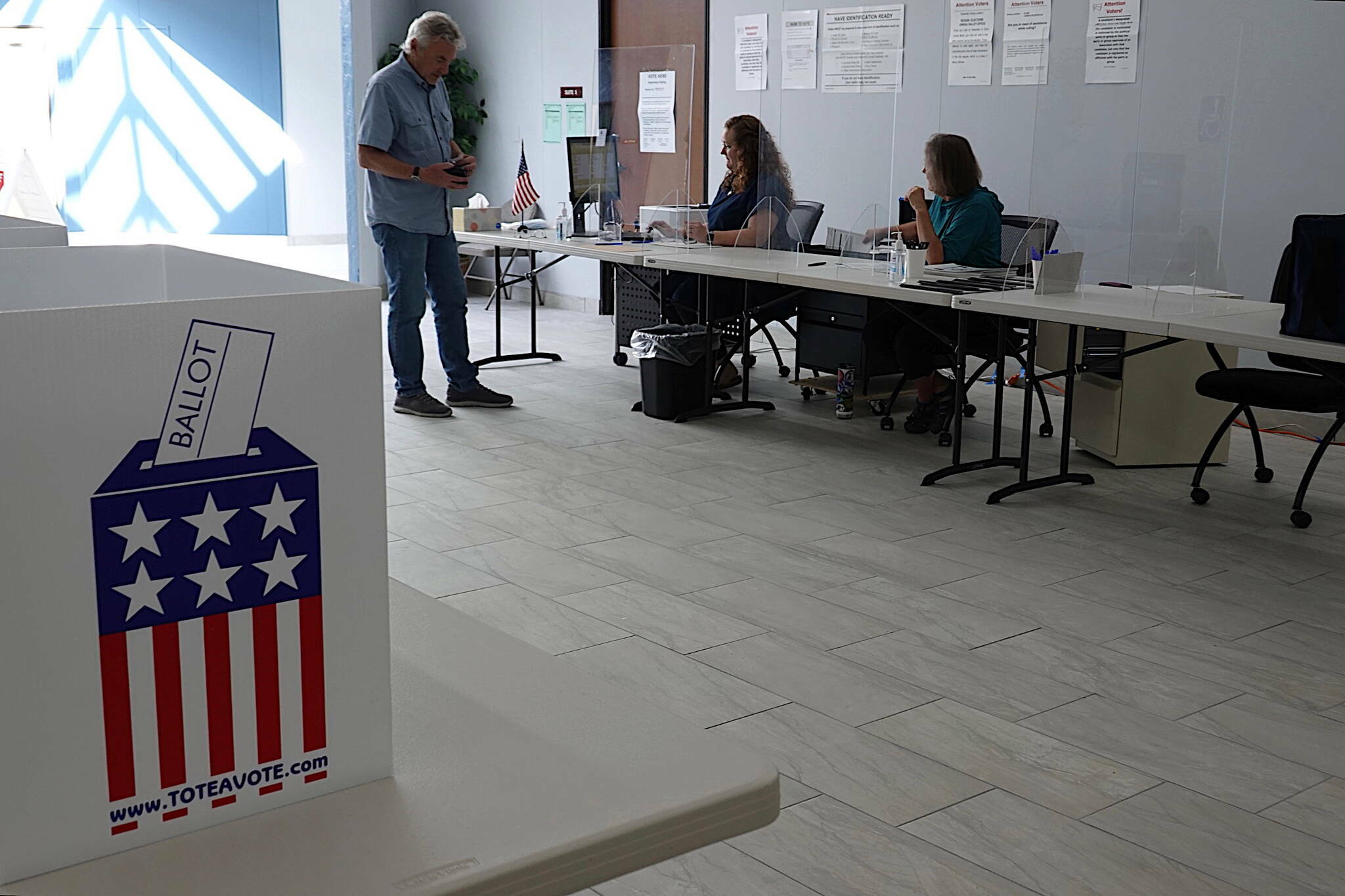 Bruce Scandling receives his ballot for Alaska’s primary election at the Mendenhall Mall Annex on Aug. 17 from election officials Jackie Rosenbruch and Barb Murray. (Laurie Craig / Juneau Empire file photo)