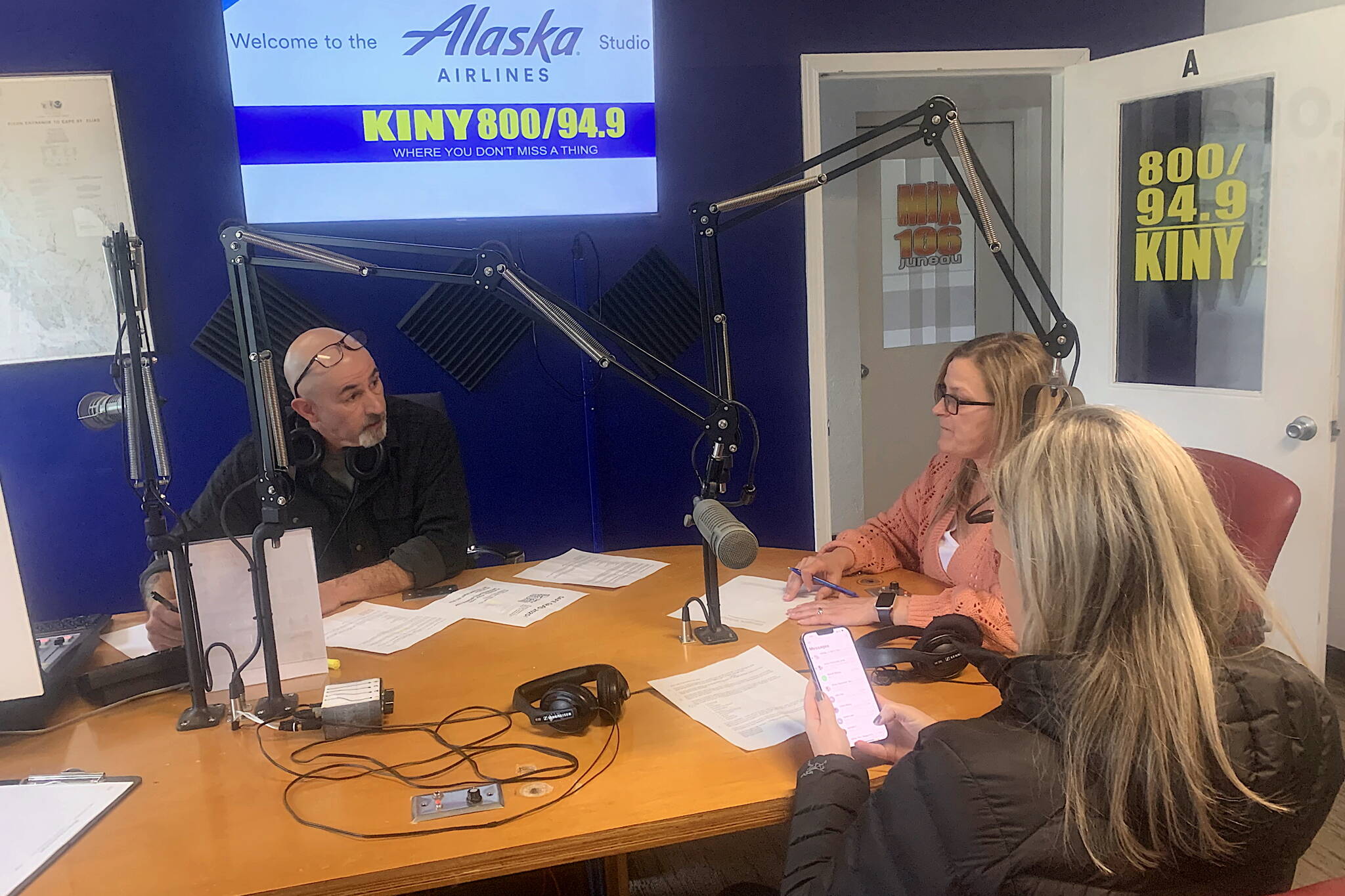 Mike Lane (left), talks to guests Brandi Billings (wearing pink) and Jessica Geary minutes before the first live broadcast in eight months of KINY-AM’s “Problem Corner” on Monday. (Mark Sabbatini / Juneau Empire)