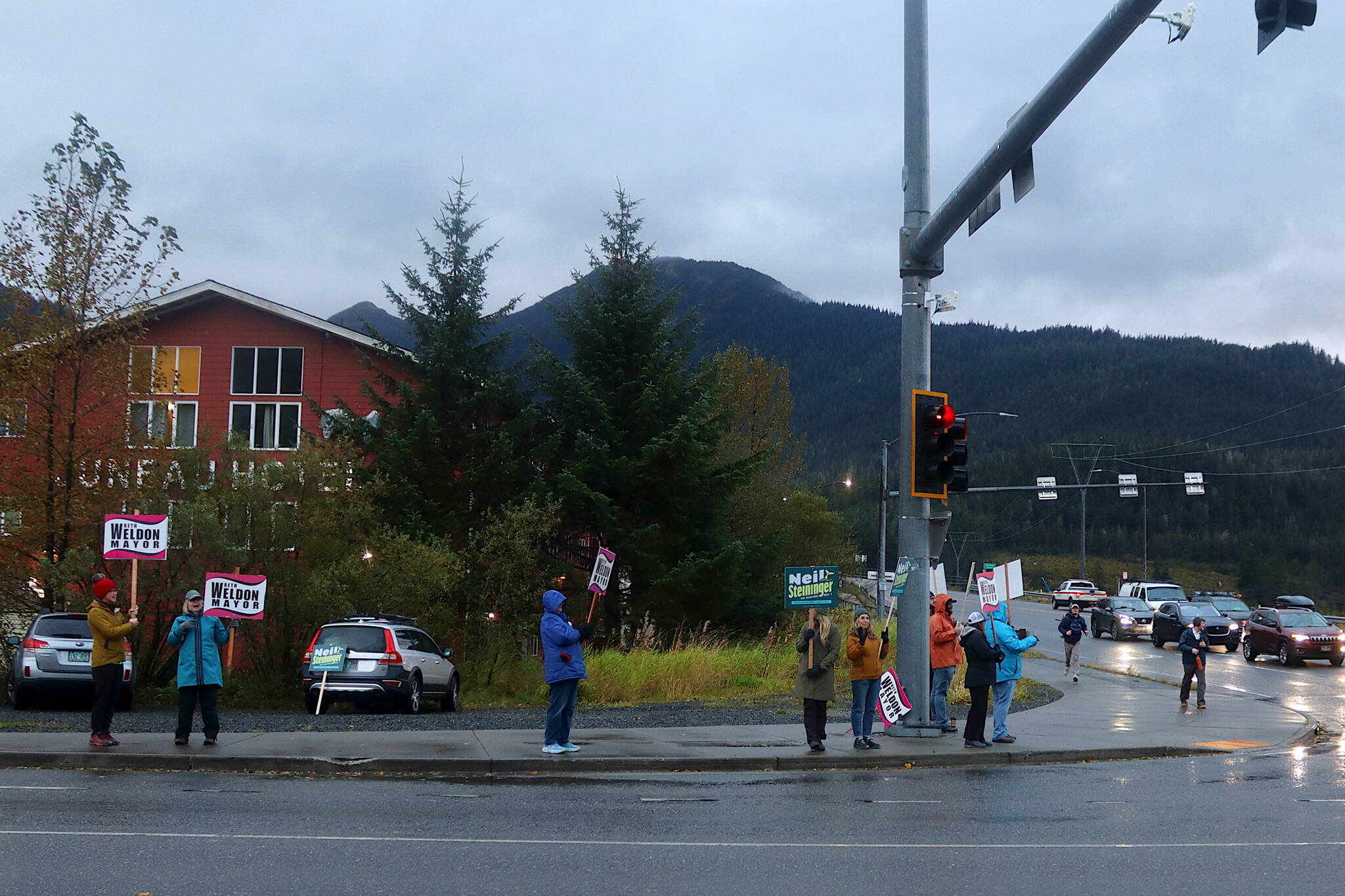 Supporters of Mayor Beth Weldon and Juneau Assembly candidate Neil Steininger wave signs to motorists on Egan Drive at the Douglas Bridge intersection on Tuesday morning. Both are well ahead in their two-candidate races in the first batch of ballots tallied Tuesday night, with official results scheduled to be certified on Oct. 15. (Mark Sabbatini / Juneau Empire)