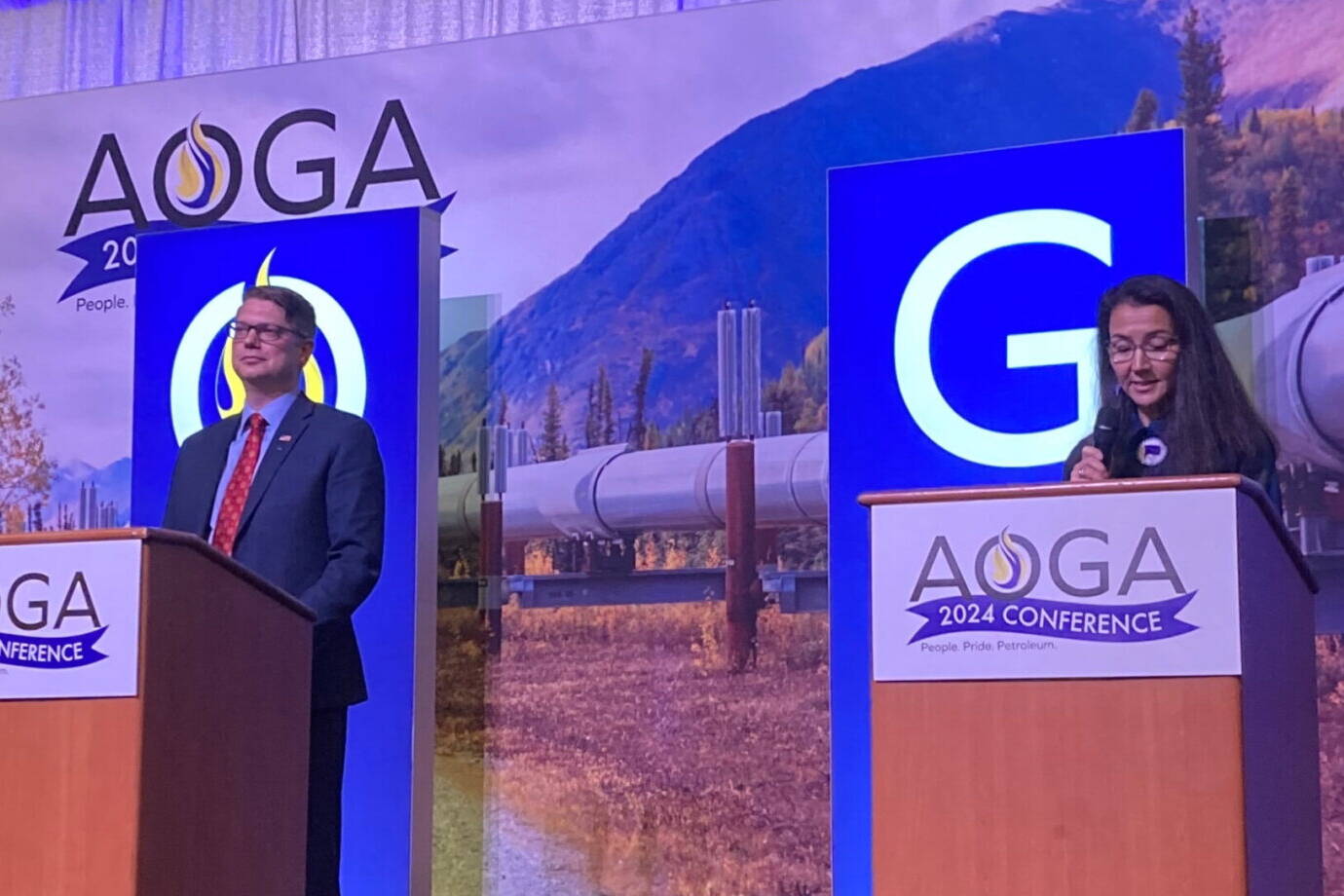 Republican challenger Nick Begich III and Democratic U.S. Rep. Mary Peltola are on the stage at the beginning of the Alaska Oil and Gas Association’s candidate forum on Aug. 28, 2024. (Andrew Kitchenman/Alaska Beacon)