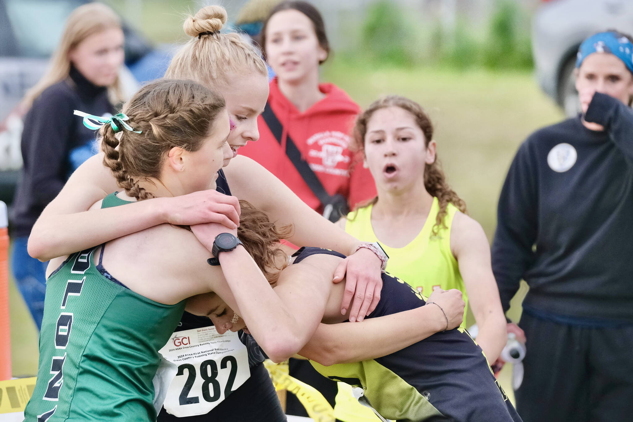 Exhausted at the finish Colony senior third-place race finisher Ella Hopkins, JDHS senior second-place finisher Ida Meyer, and Anchorage junior fourth-place finisher Mia Stiassny hug as Wasilla sophomore race winner Hailee Giacobbe approaches to congratulate them at the Division I girls 2024 ASAA cross-country running state championships Saturday on the Bartlett High School Trails in Anchorage. (Klas Stolpe / Juneau Empire)