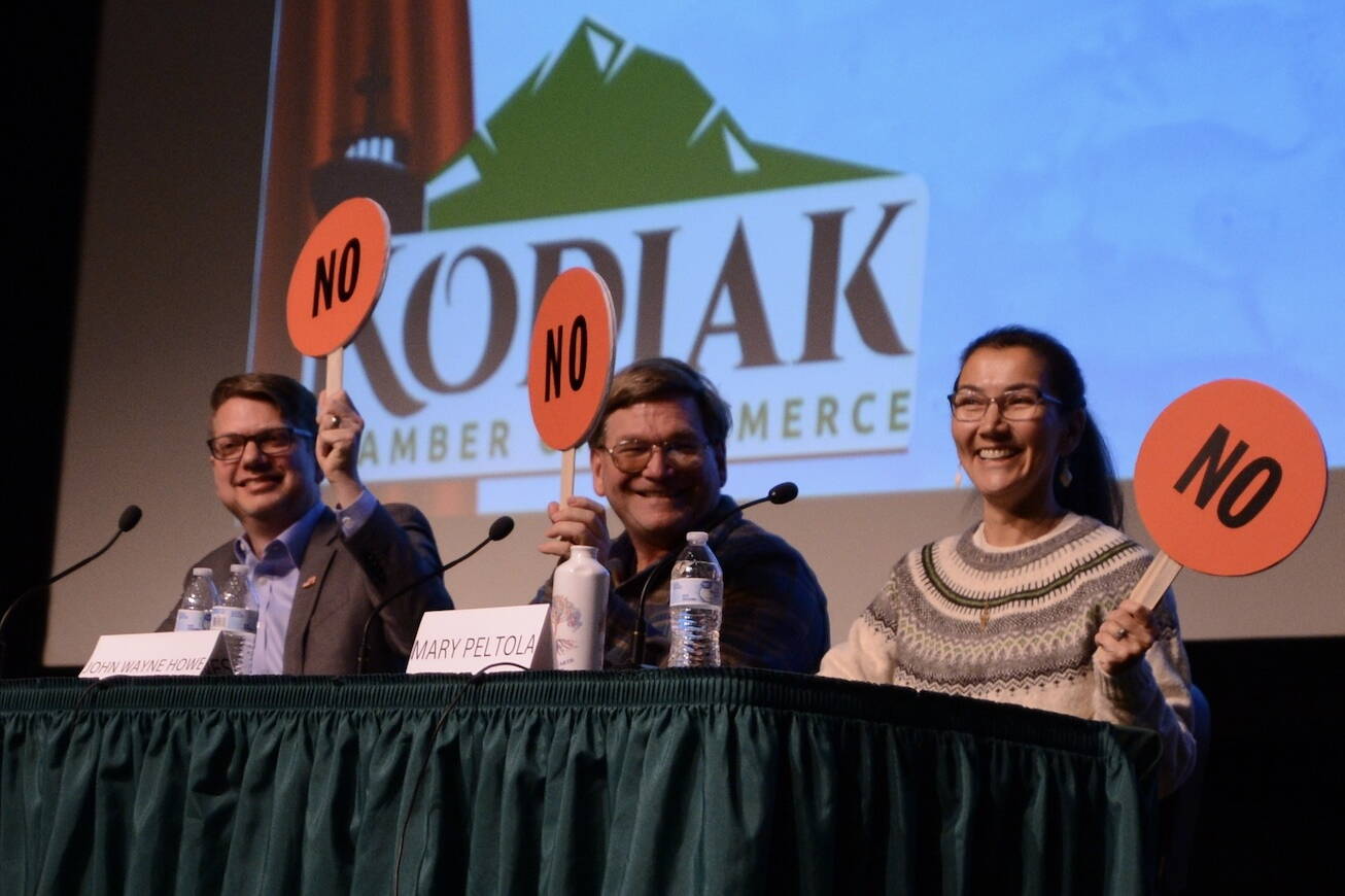 From left to right, Nick Begich, Republican candidate for U.S. House; Alaskan Independence Party candidate John Wayne Howe and Rep. Mary Peltola, D-Alaska, hold up paddles indicating their opposition to finfish farming in Alaska. Howe had jokingly looked at Begich’s paddle before making a decision. (James Brooks/Alaska Beacon)