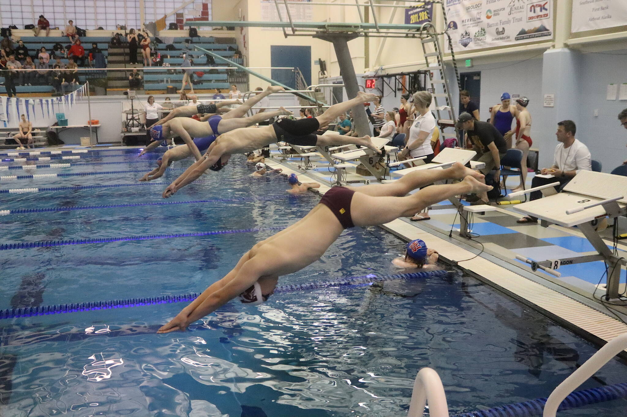 Boys dive in for a 100-meter freestyle race during a regional meet Saturday at Dimond Park Aquatic Center. (Mark Sabbatini / Juneau Empire)