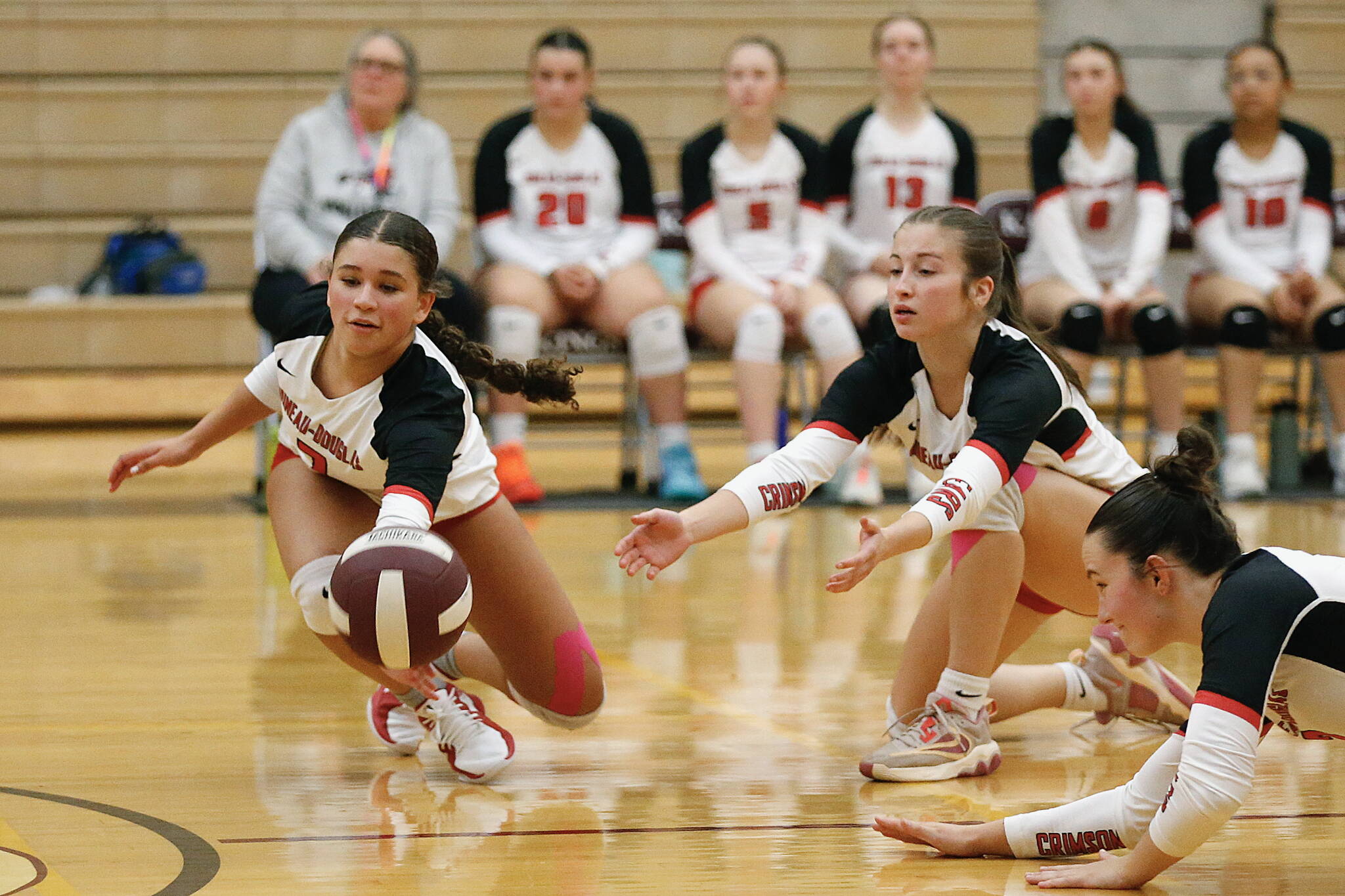 Juneau-Douglas High School: Yadaa.at Kalé’s Leila Cooper, June Troxel and Braith Dihle dive for the ball during their 25-19, 25-16, 25-15 victory over Ketchikan High School at the Clarke Cochrane Gymnasium on Saturday, Oct. 12, 2024. (Christopher Mullen/ Ketchikan Daily News)