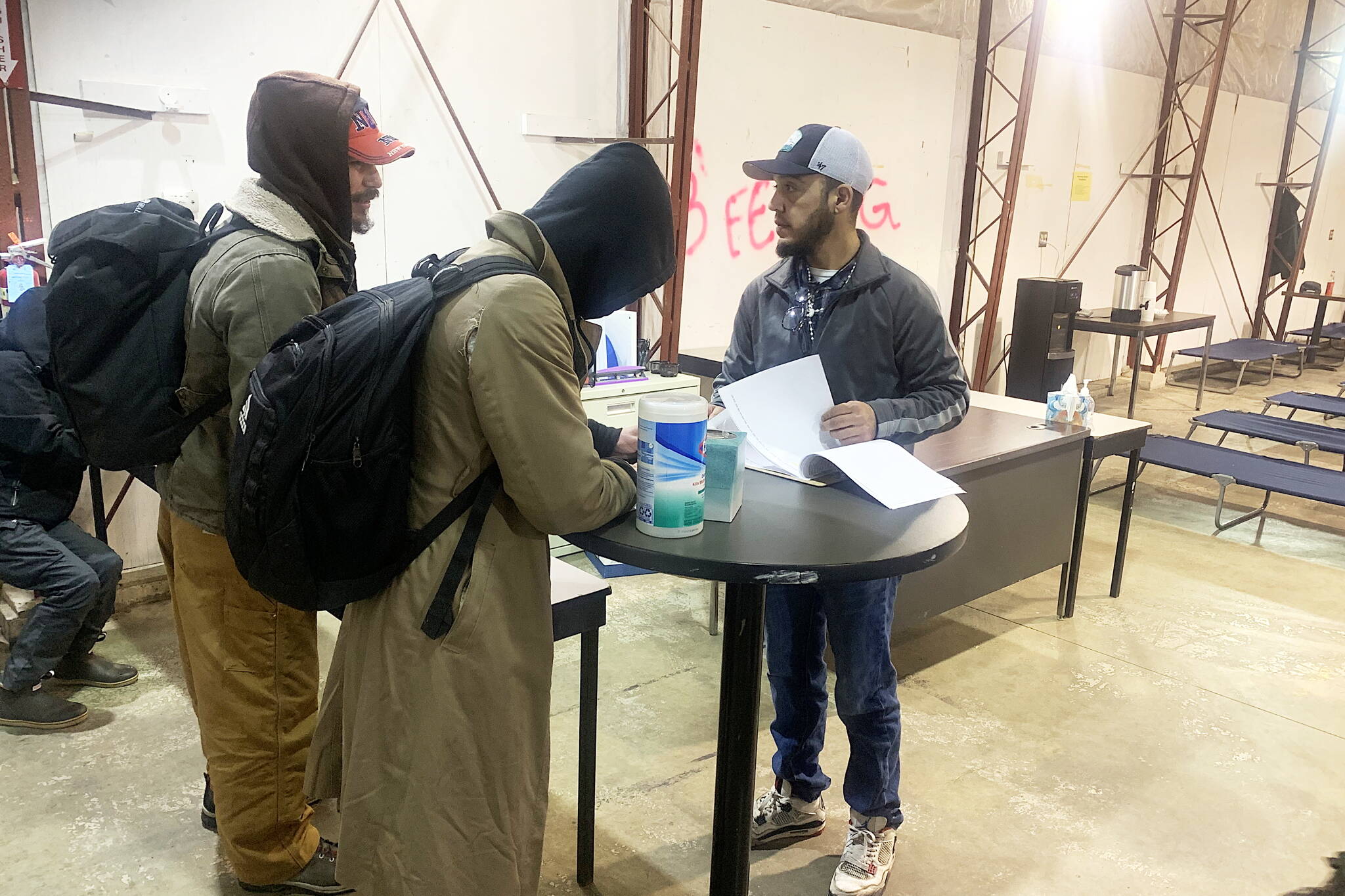 Juvencio Garcia (right) has people sign in to stay at the city’s cold-weather emergency shelter in Thane on the first night of its second year of operation Tuesday. Garcia was among those who stayed at the shelter last year and said he hopes to provide the help shelter staff from the first season provided him. (Mark Sabbatini / Juneau Empire)