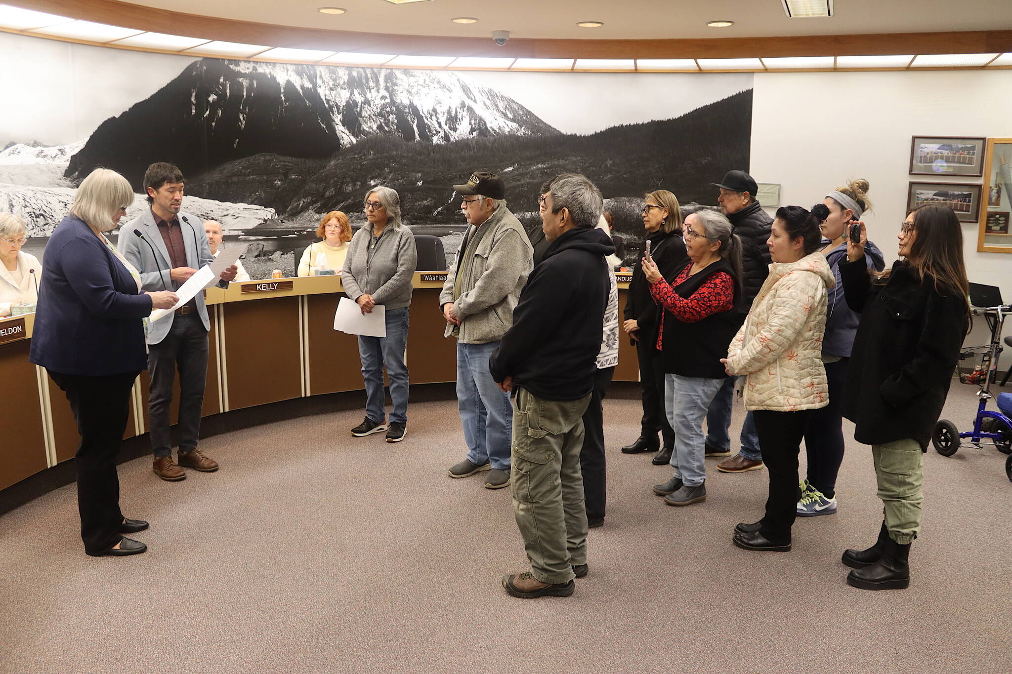 Juneau Mayor Beth Weldon and Assembly member Greg Smith (left) read a formal apology to member of the Douglas Indian Association during an Assembly meeting Monday night, acknowledging the City and Borough of Juneau’s role in the burning of the Douglas Indian Village in 1962. (Mark Sabbatini / Juneau Empire)