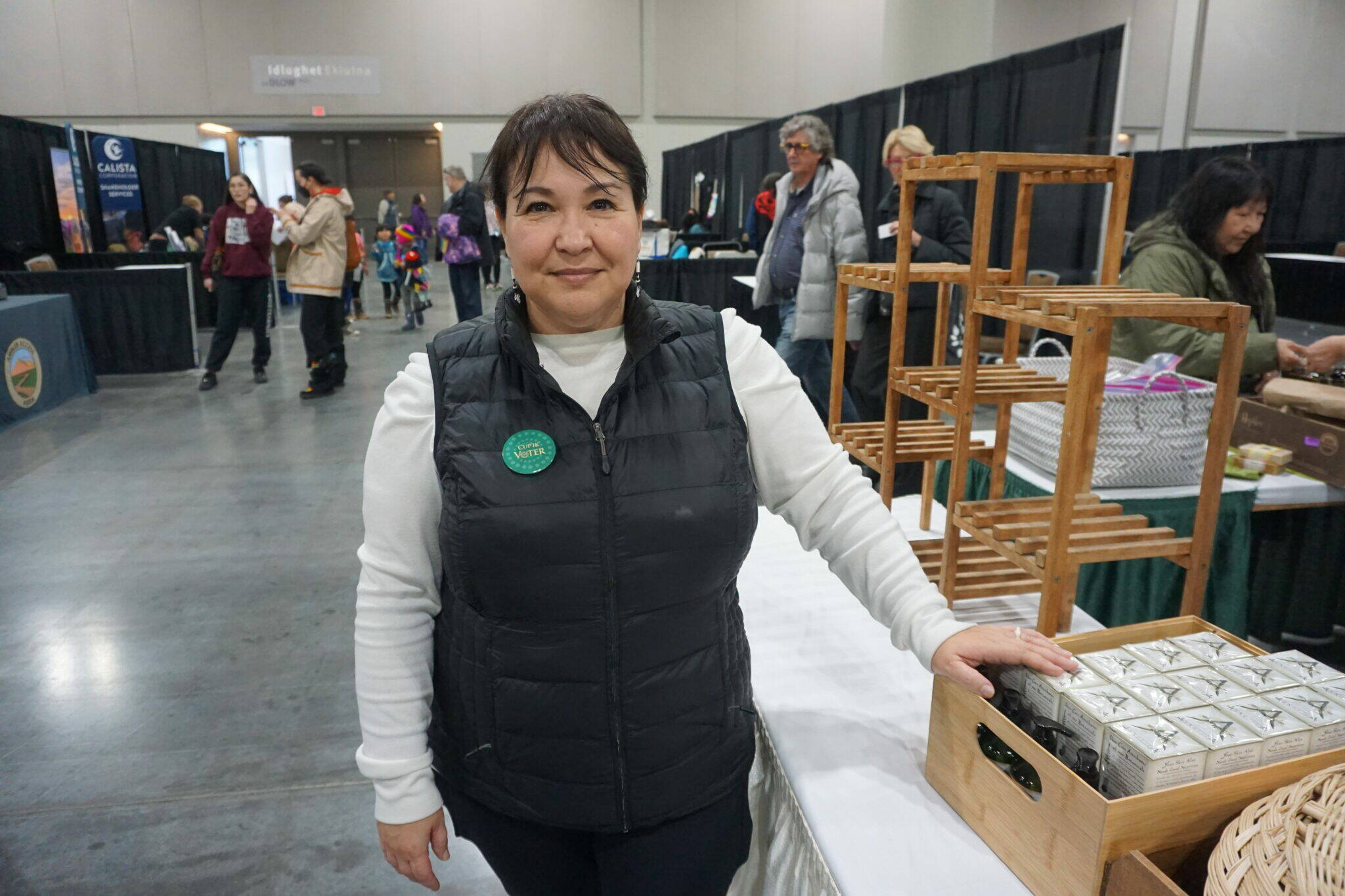 Michelle Sparck, director of Get Out The Native Vote, stands by her business’ booth on Saturday at the Alaska Federation of Natives convention in Anchorage. Sparck, wearing a button identifying her as a Cup’ik voter, is urging Alaska Natives to be more diligent about voting in both state and local elections. In addition to her voter-education work, Sparck has a beauty-products business, ArXotica, that she and her sisters founded. (Yereth Rosen/Alaska Beacon)