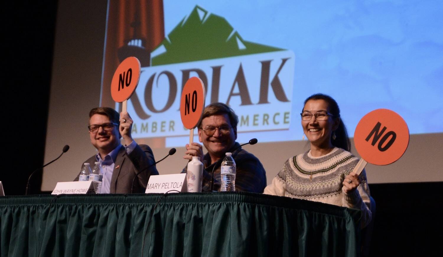 From left to right, Nick Begich, Republican candidate for U.S. House; Alaskan Independence Party candidate John Wayne Howe and Rep. Mary Peltola, D-Alaska, hold up paddles indicating their opposition to finfish farming in Alaska. Howe and imprisoned out-of-state Democrat Eric Hafner are receiving attention from the leading campaigns. (James Brooks/Alaska Beacon)