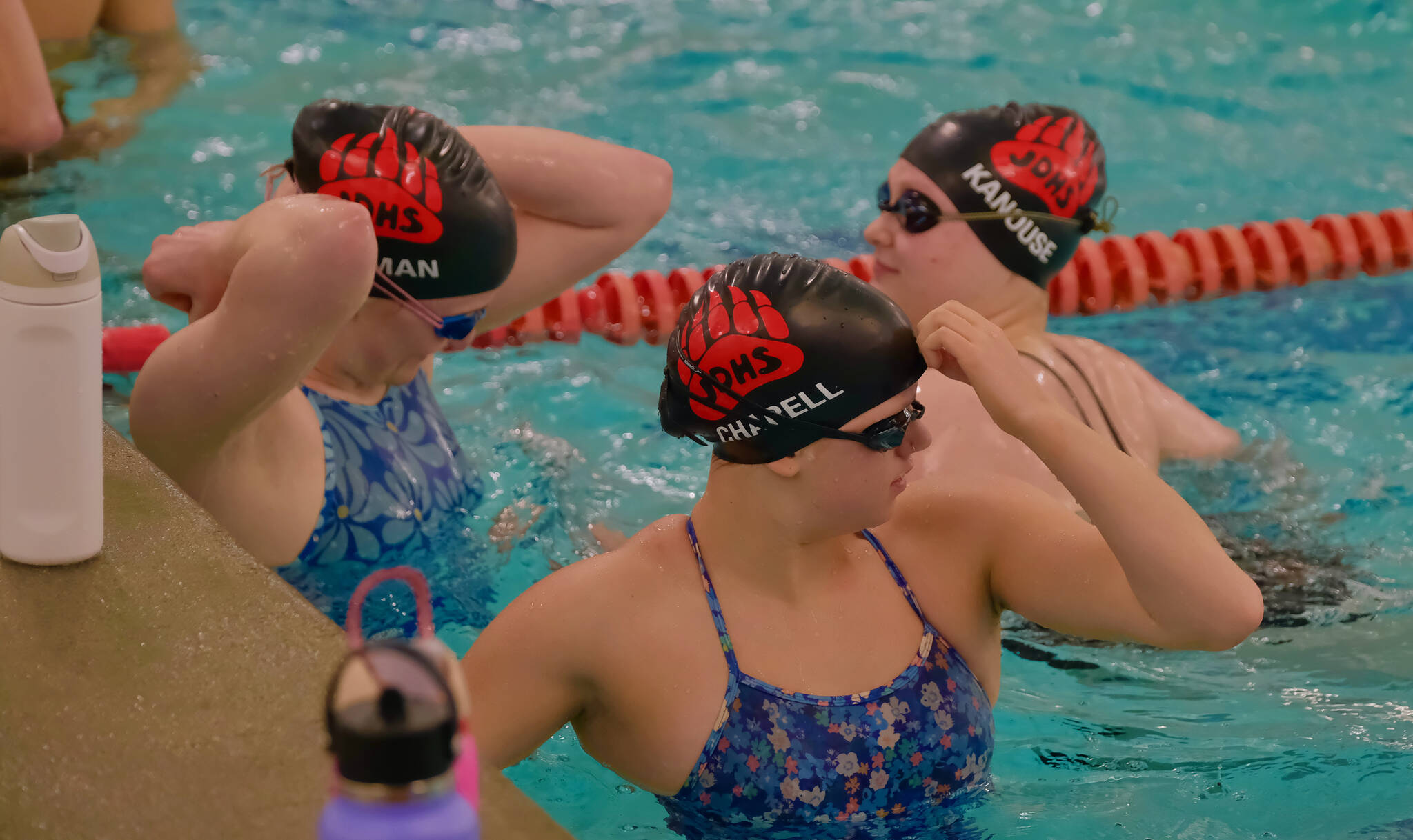 Juneau-Douglas High School: Yadaa.at Kalé seniors Parker Boman, Lucia Chapell and Brooklyn Kanouse sport the teams new official JDHS Crimson Bears swim caps during practice Tuesday at Augustus Brown Pool in preparation for the Region V Swim & Dive Championships in Petersburg this weekend. (Klas Stolpe / Juneau Empire)