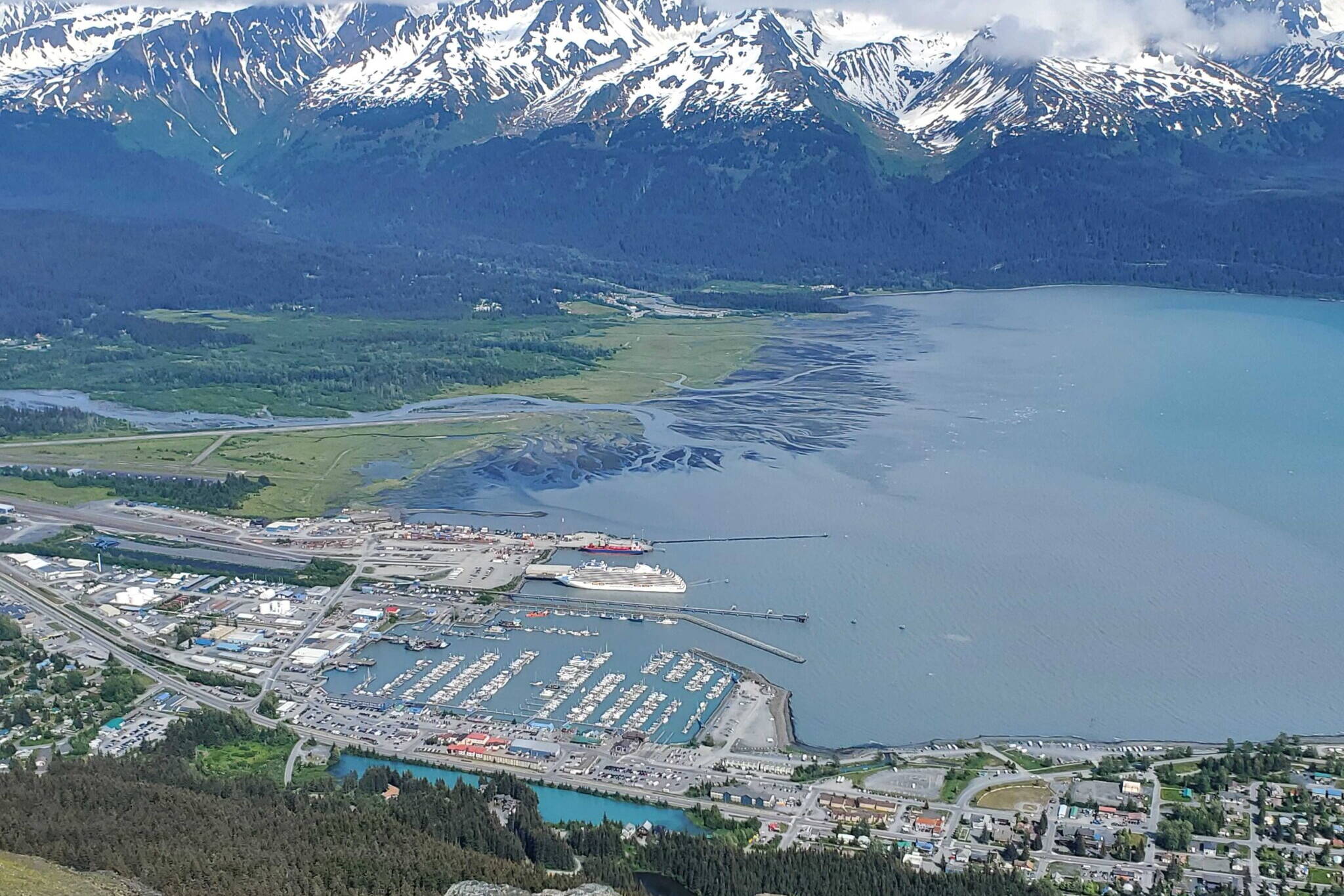 A docked cruise ship, the Regent Seven Seas Explorer, is seen in Seward’s harbor on June 19 from the Race Point on Mount Marathon. The Port of Seward received a Clean Ports Program grant from the Environmental Protection Agency for a shore-based system to power cruise ships when they are docked in town. (Yereth Rosen/Alaska Beacon)