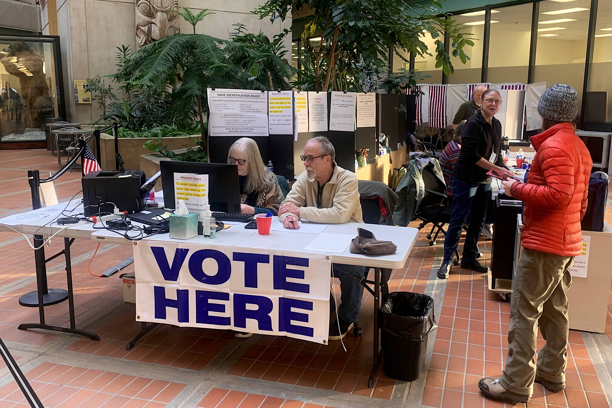 A voter talks to election officials at a early voting station at the State Office Building on Monday. Alaskans, like the rest of the U.S., are casting early ballots at a record pace ahead of Tuesday’s election. (Mark Sabbatini / Juneau Empire)